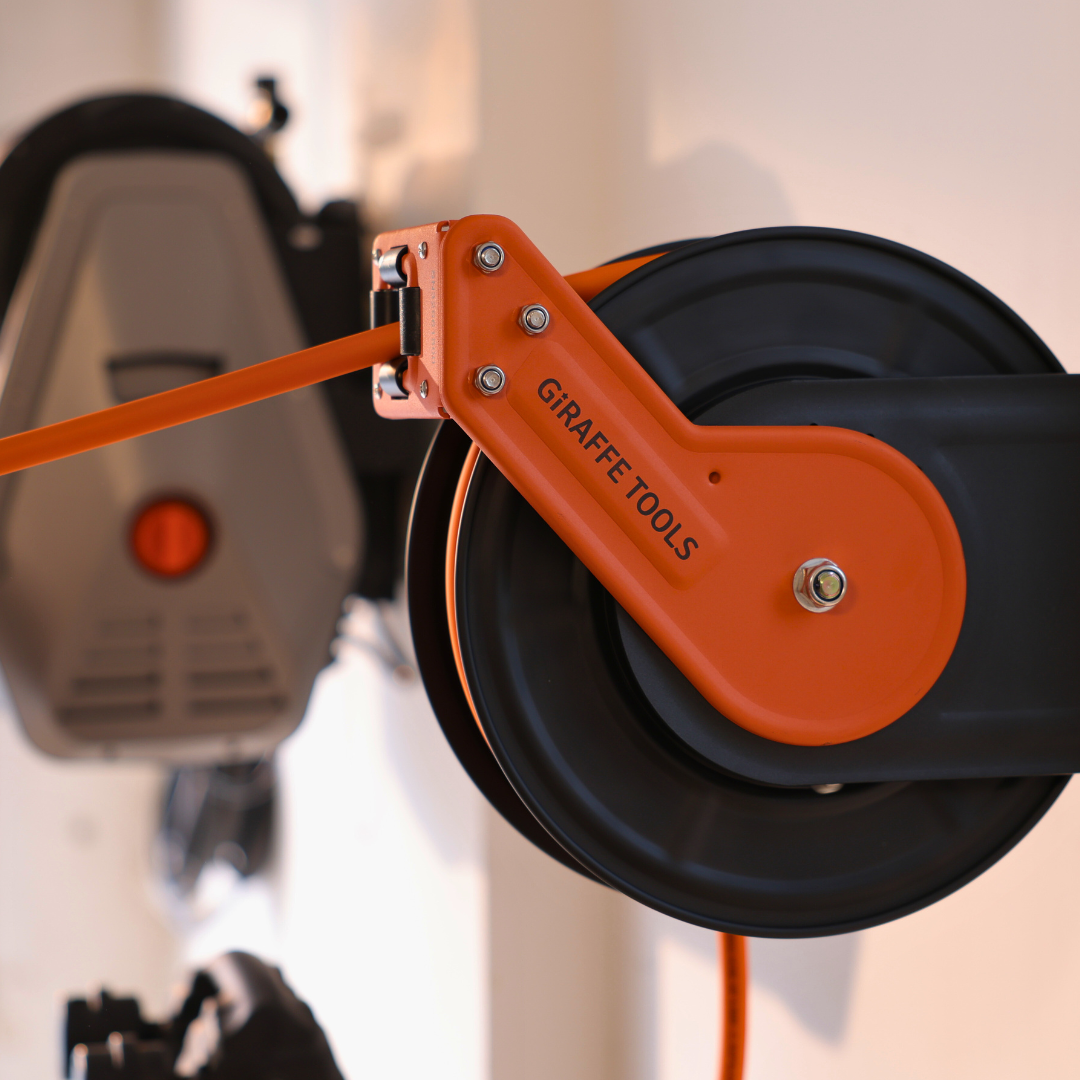 Orange retractable air hose reel mounted to a wall bracket