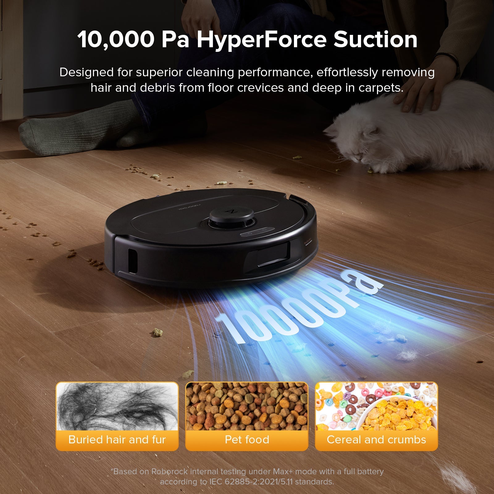 Black robot vacuum on hardwood floor near scattered debris and fur traces