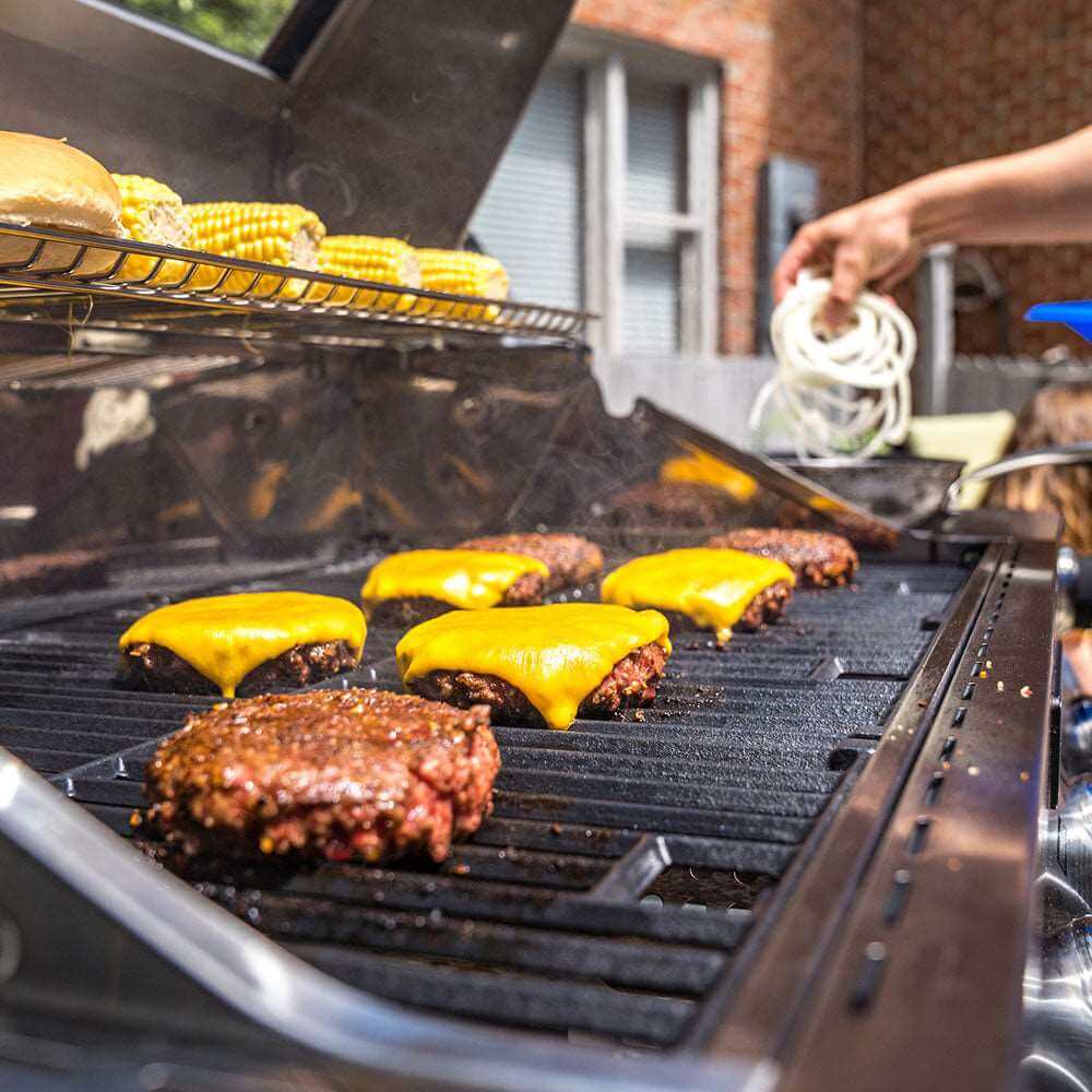 Stainless steel gas grill grates with burgers and melted cheese