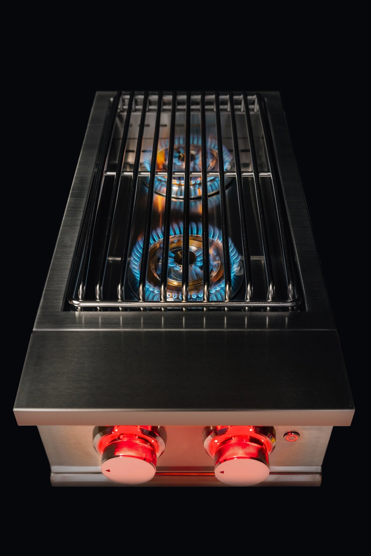 Double natural gas side burner top view with metal grates and blue flames