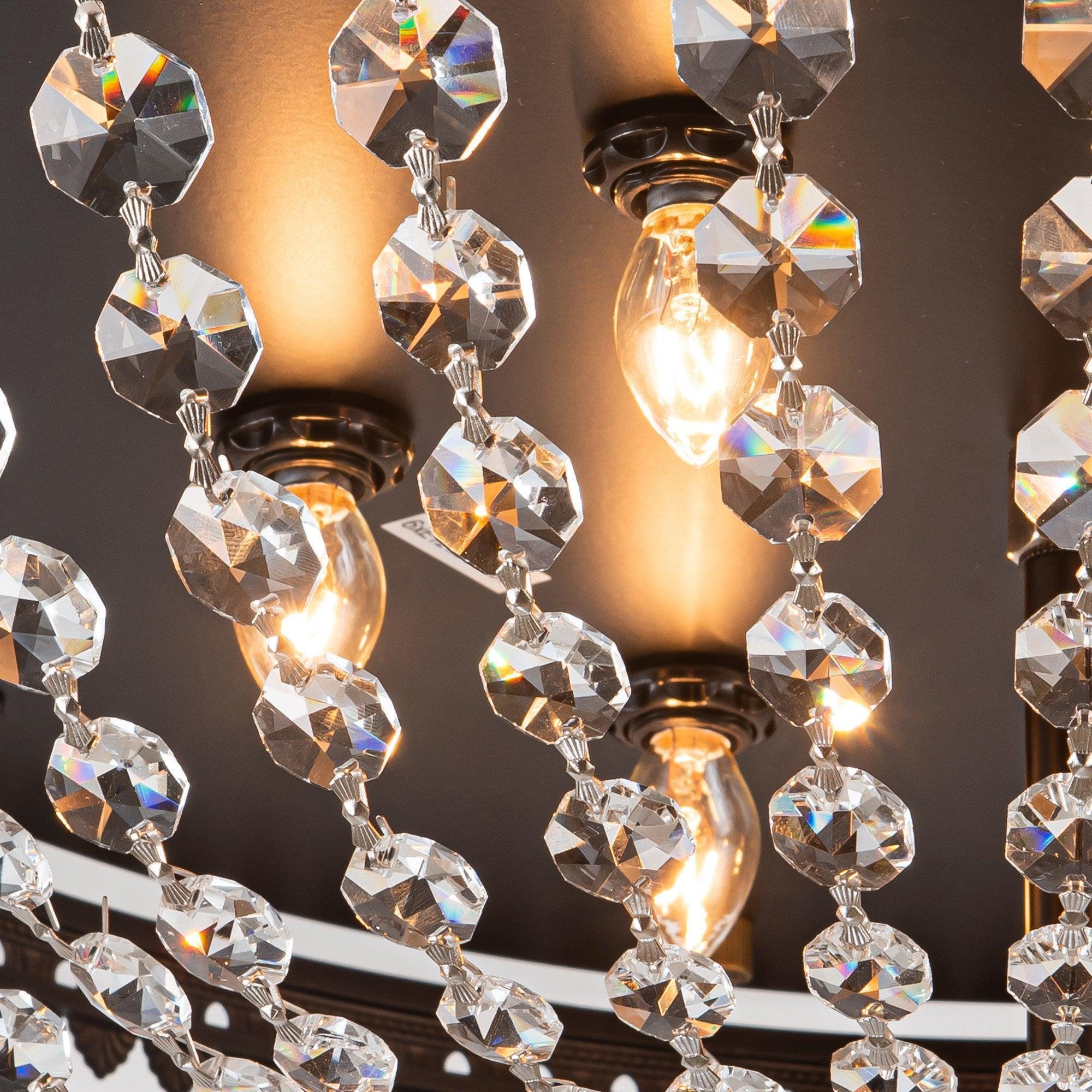 Close-up of crystal prisms and glowing bulbs on a dark ceiling fan light