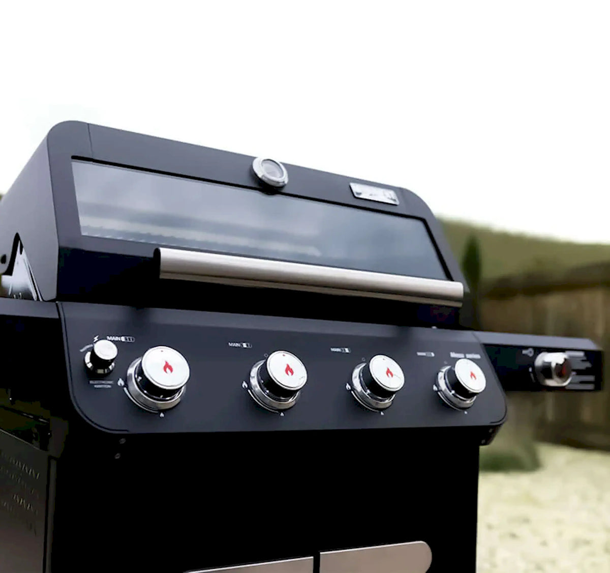 Black 4-burner gas grill lid and front control panel with four knobs
