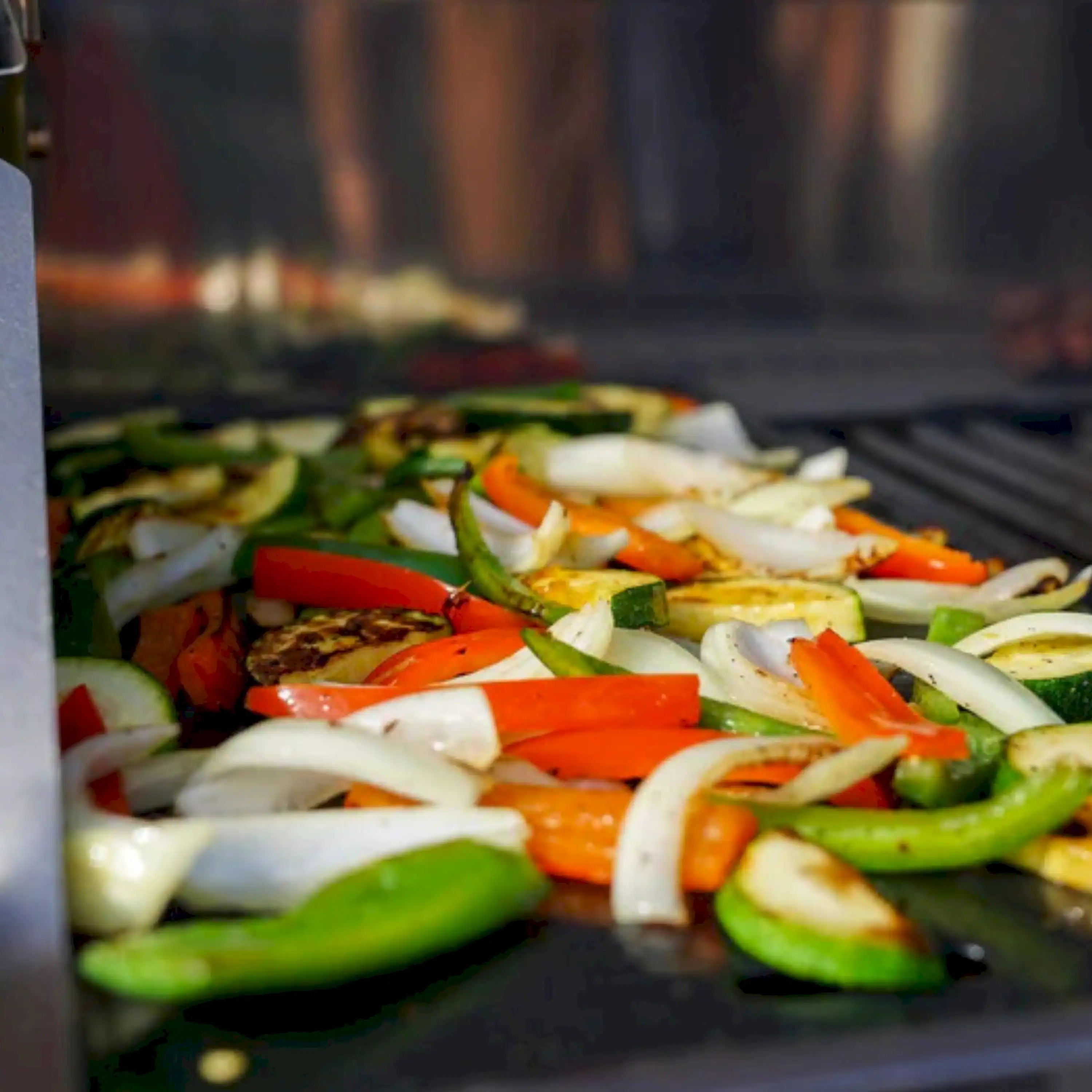 Vegetables on a dark cast iron grill plate with raised ridges in a grill