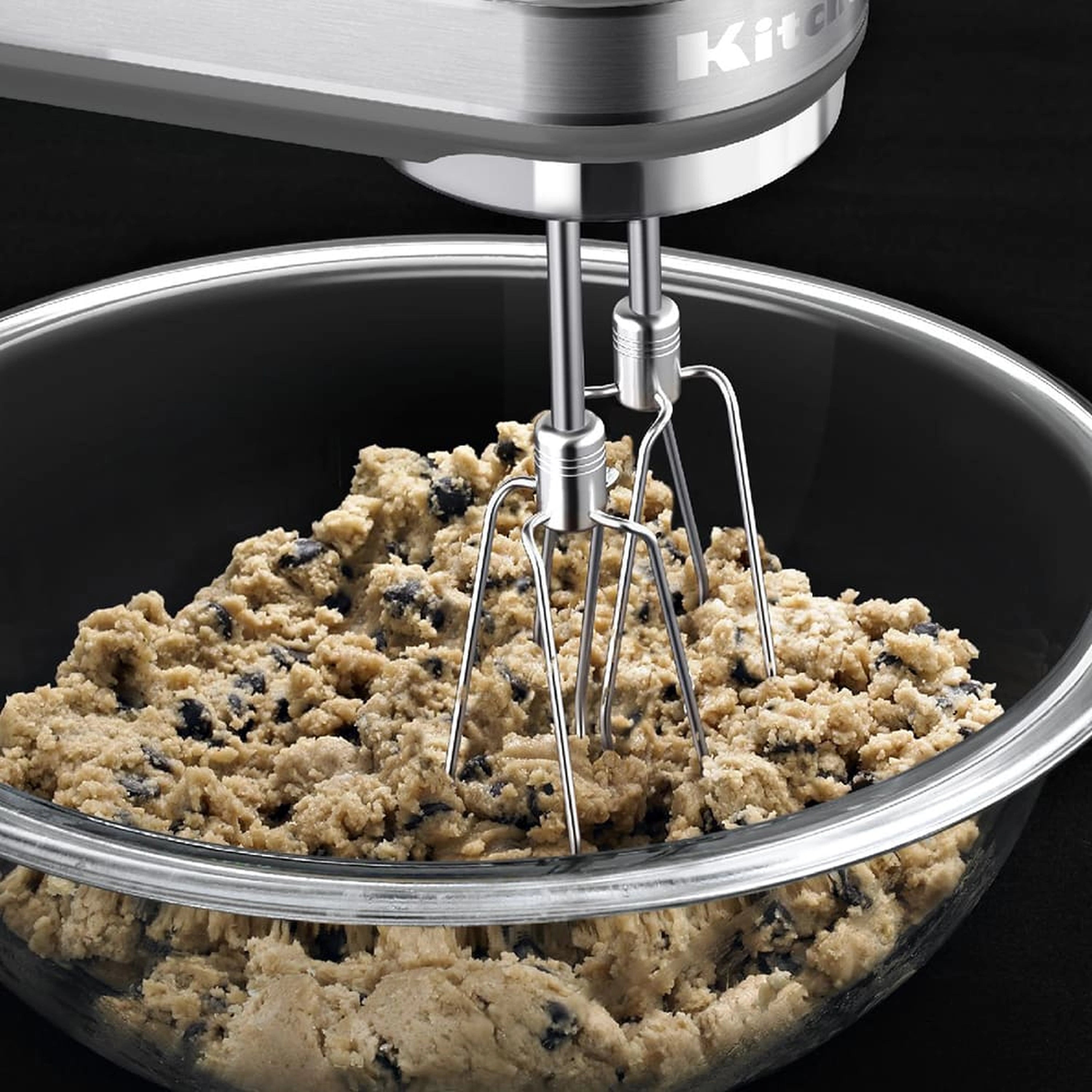Stainless hand mixer beating cookie dough in mixing bowl with turbo beaters