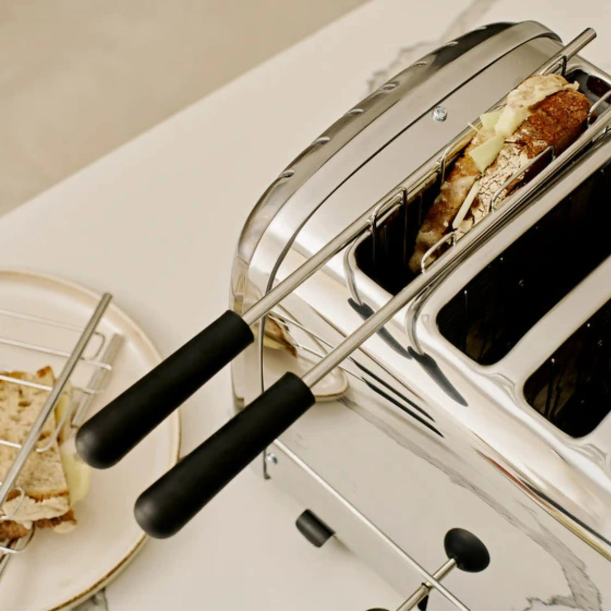 Dualit chrome sandwich cage with black handles, open with filled sandwich