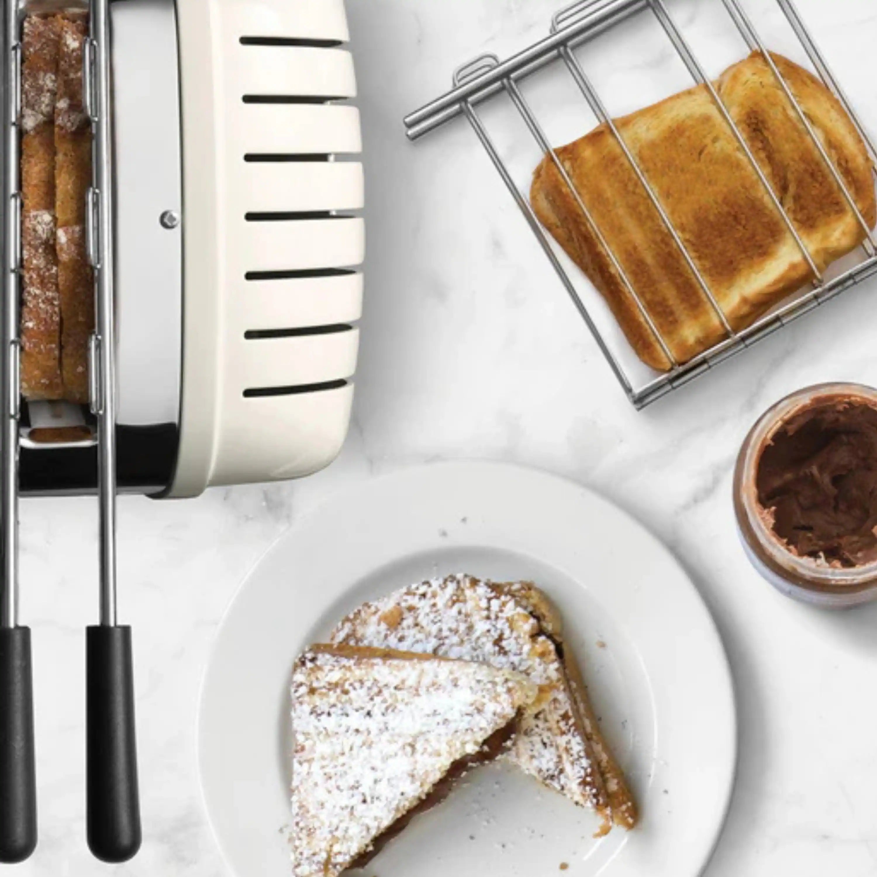 Chrome toaster and cage rack with square toast, bread slice plate, and dish nearby