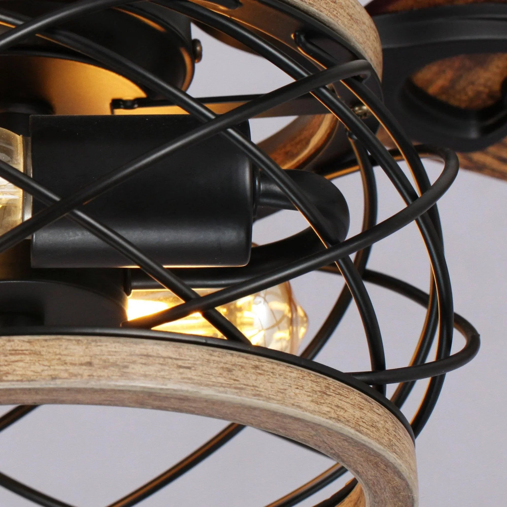 Detail view of black caged light and wood blade edge on a ceiling fan