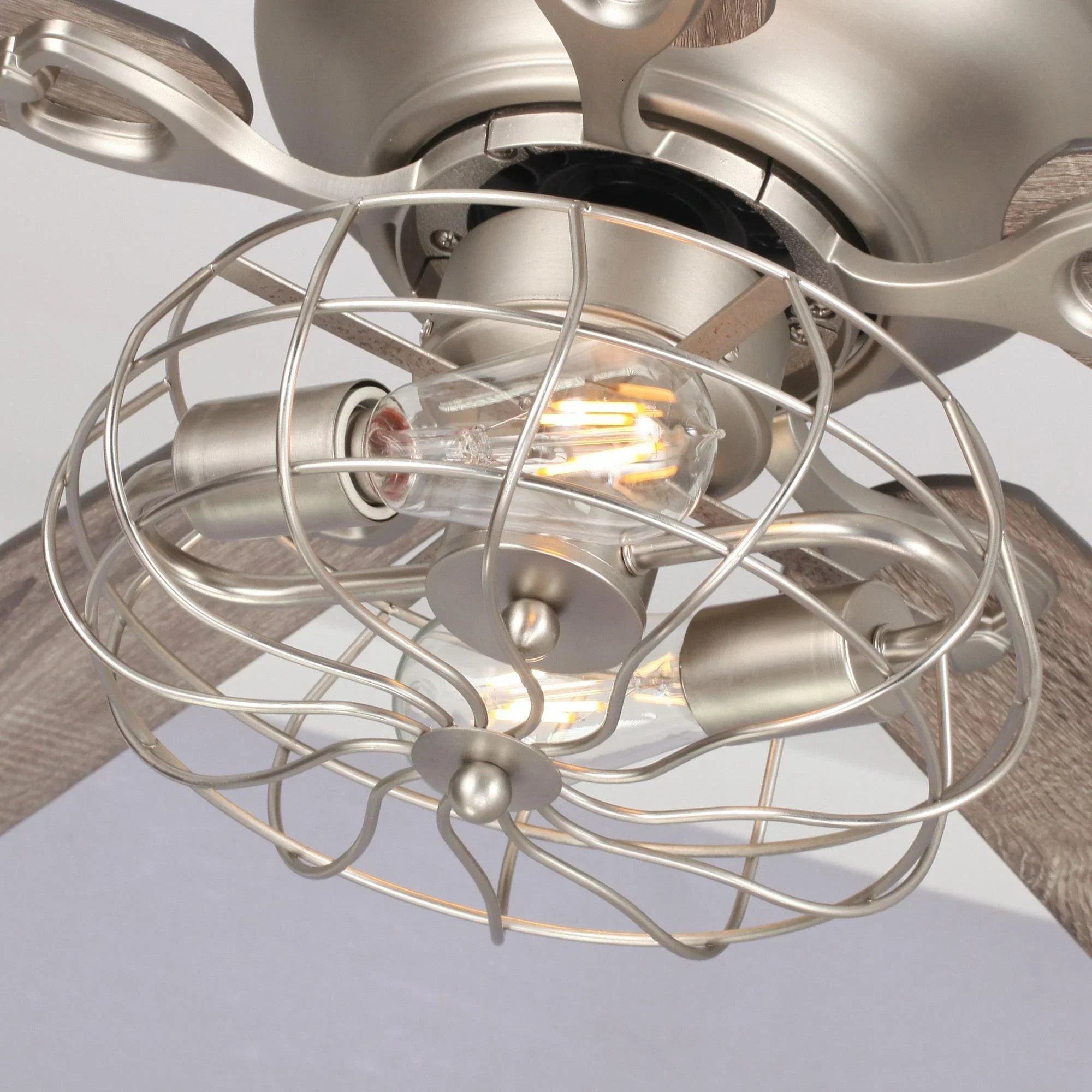 Close-up of wire light cage and lit bulbs on a satin nickel ceiling fan