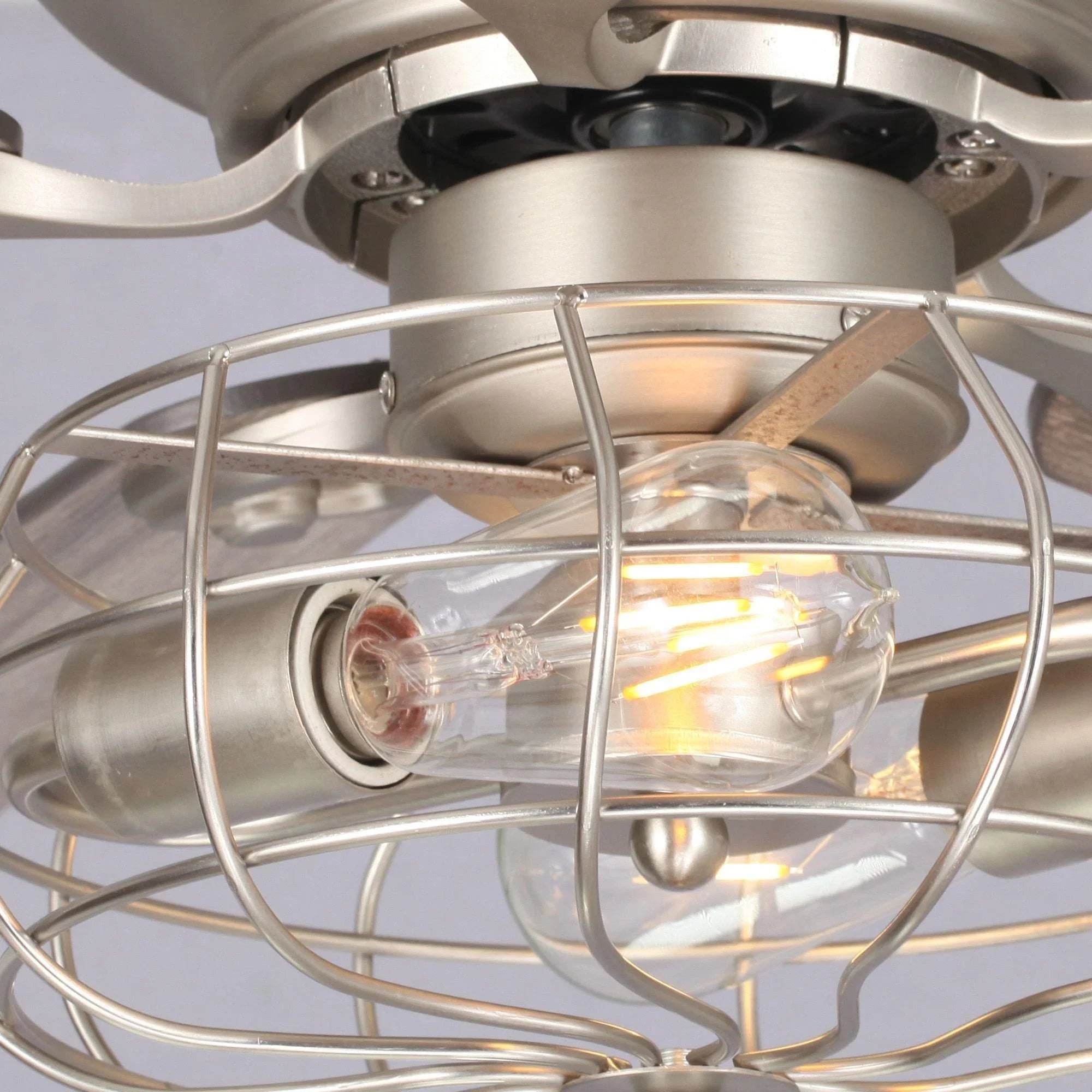 Close-up of satin nickel ceiling fan light fixture with glass bulbs in wire cage