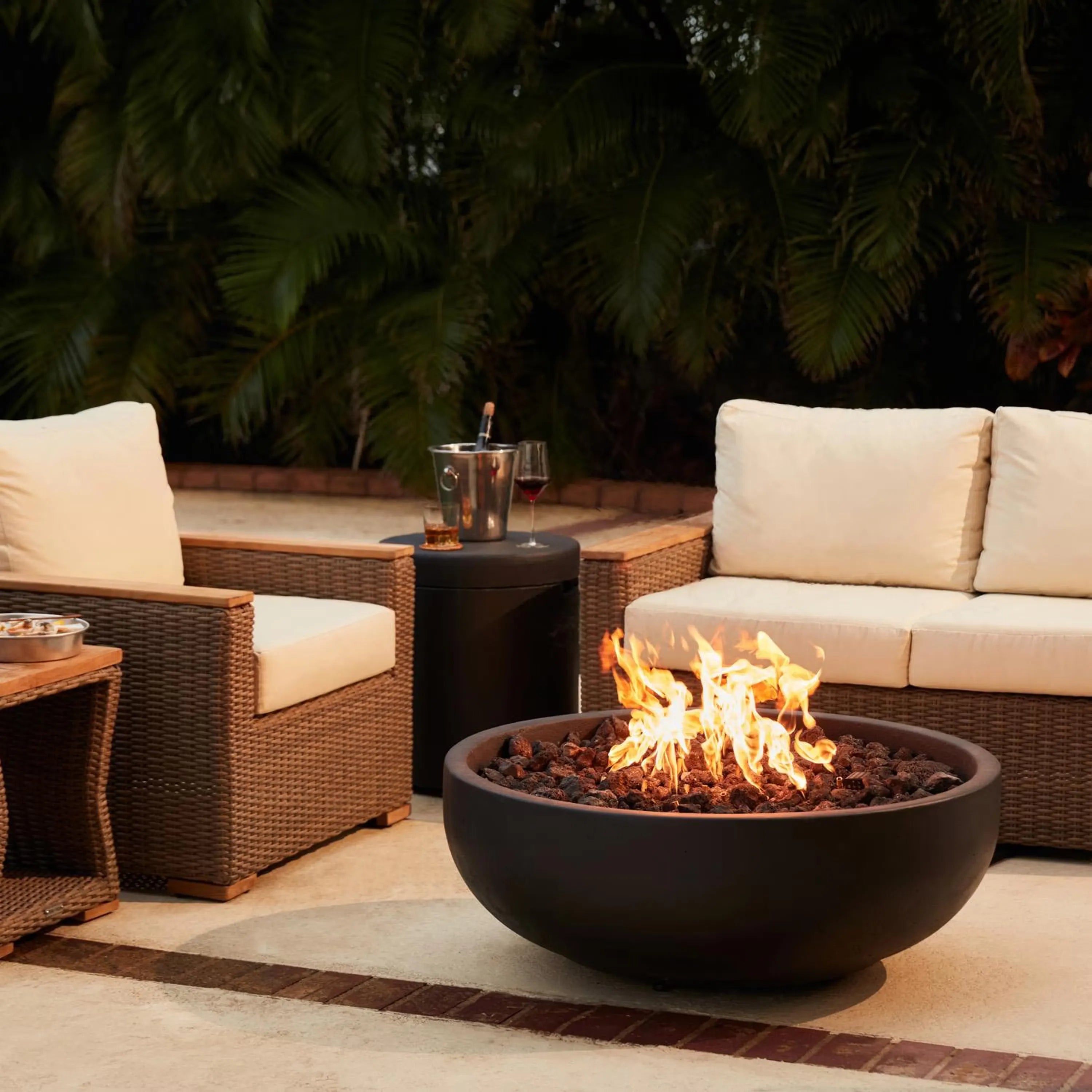 Round concrete propane fire bowl with active flames and rock burner insert