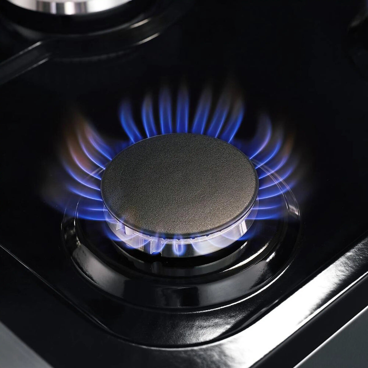 Stainless steel gas cooktop burner with blue flame, round grate and cap visible