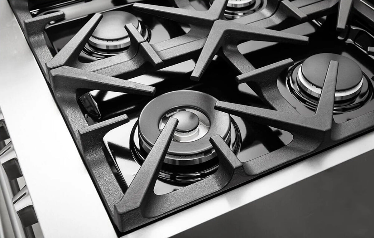 Stainless steel gas burner heads on cooktop with black grate and burner caps