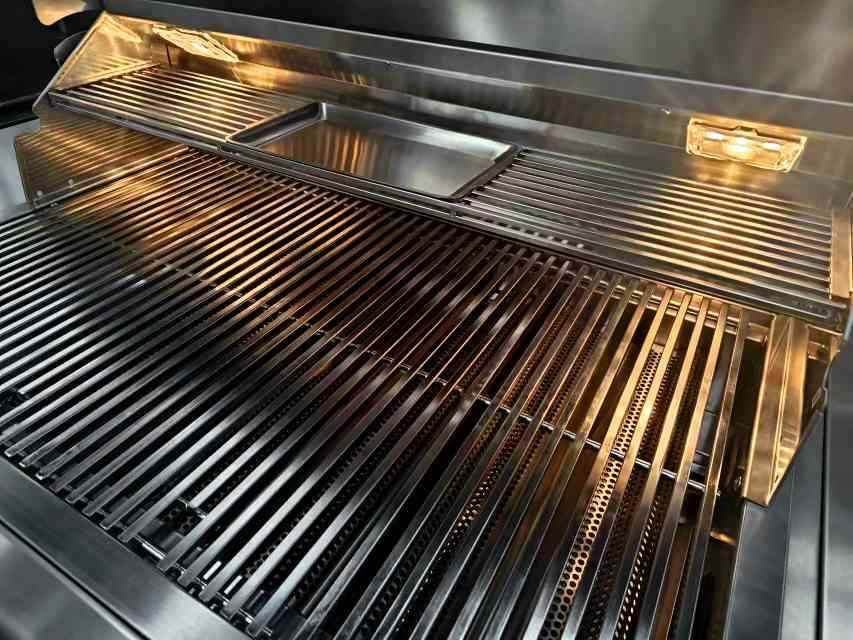 Built-in propane gas grill with stainless cooking grates and open hood
