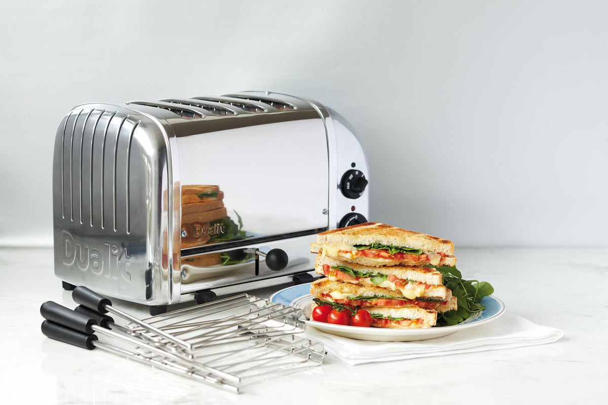 Chrome sandwich toaster with cooking rack extended and stacked sandwiches on plate