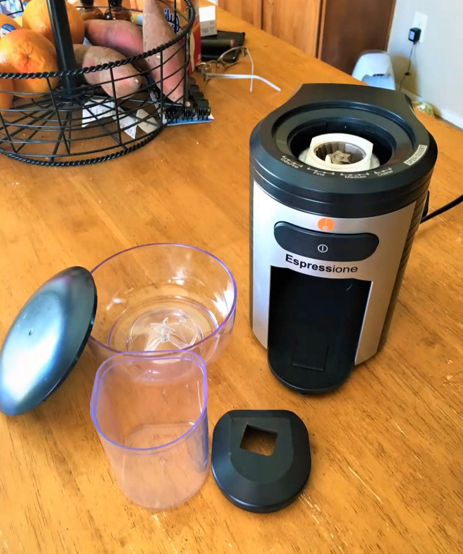Conical burr coffee grinder shown with accessory lid and clear measuring cup