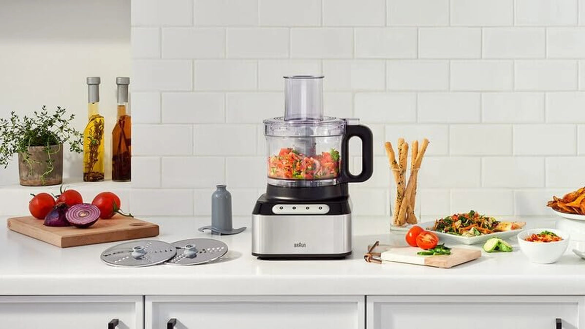 Braun food processor on counter with vegetables and ingredients, clear blending jar