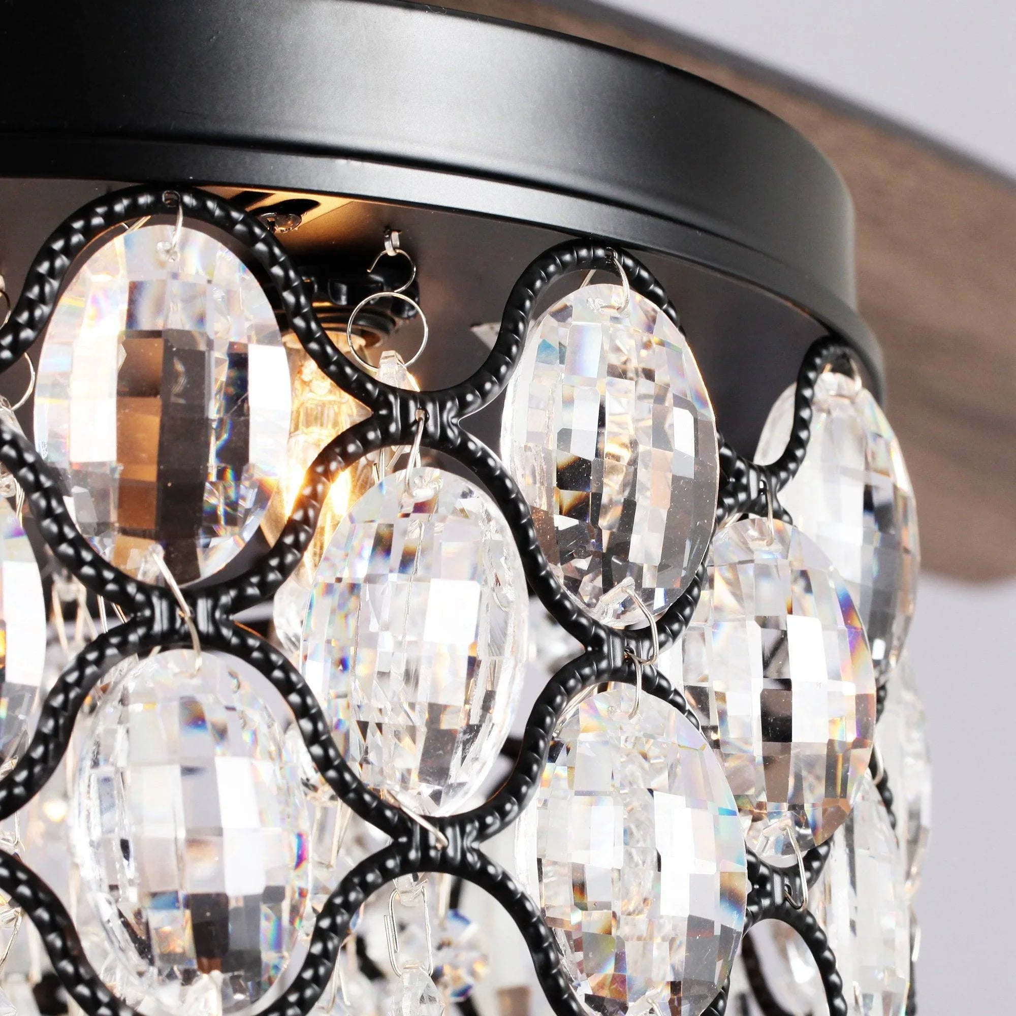 Close-up of black crystal ceiling fan light with faceted glass and glowing bulbs
