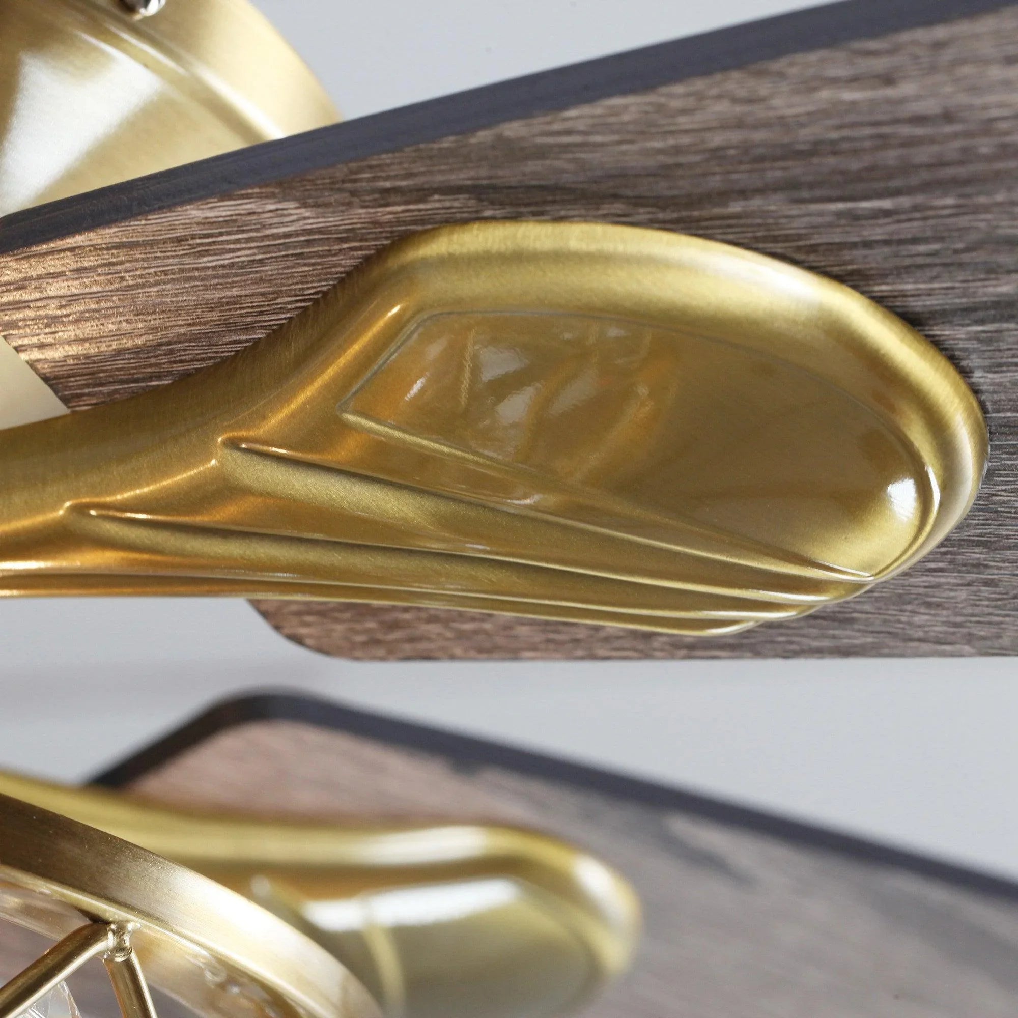 Golden ceiling fan blade arm and crystal-style light housing, close-up