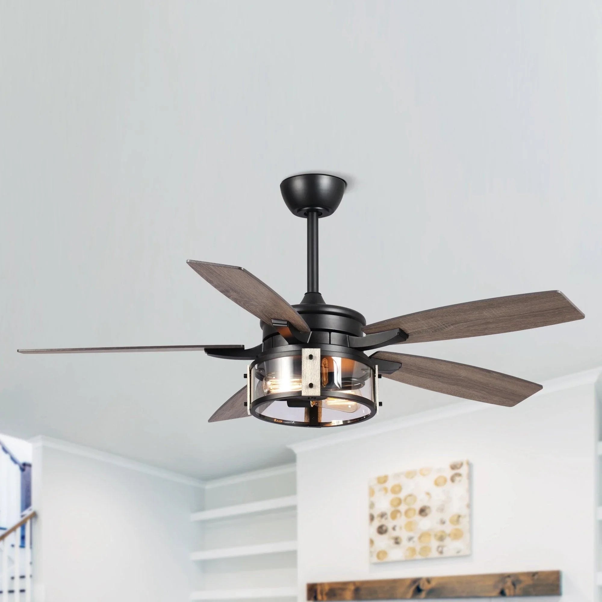 Black ceiling fan with wood-look reversible blades and lit light kit on ceiling