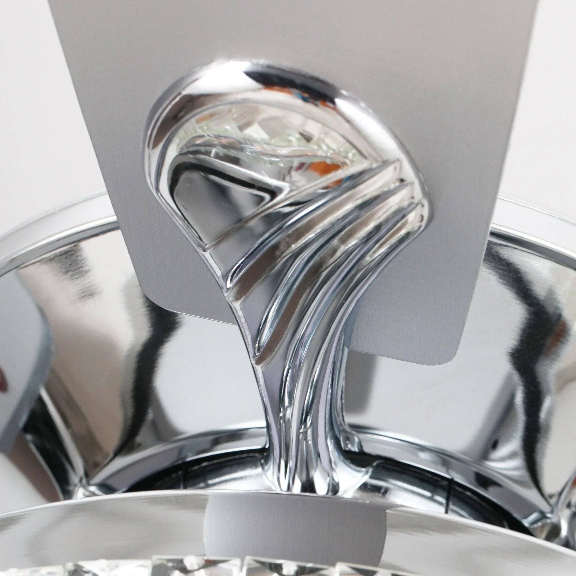 Close-up of chrome fandelier canopy and crystal-support frame, reflective finish.