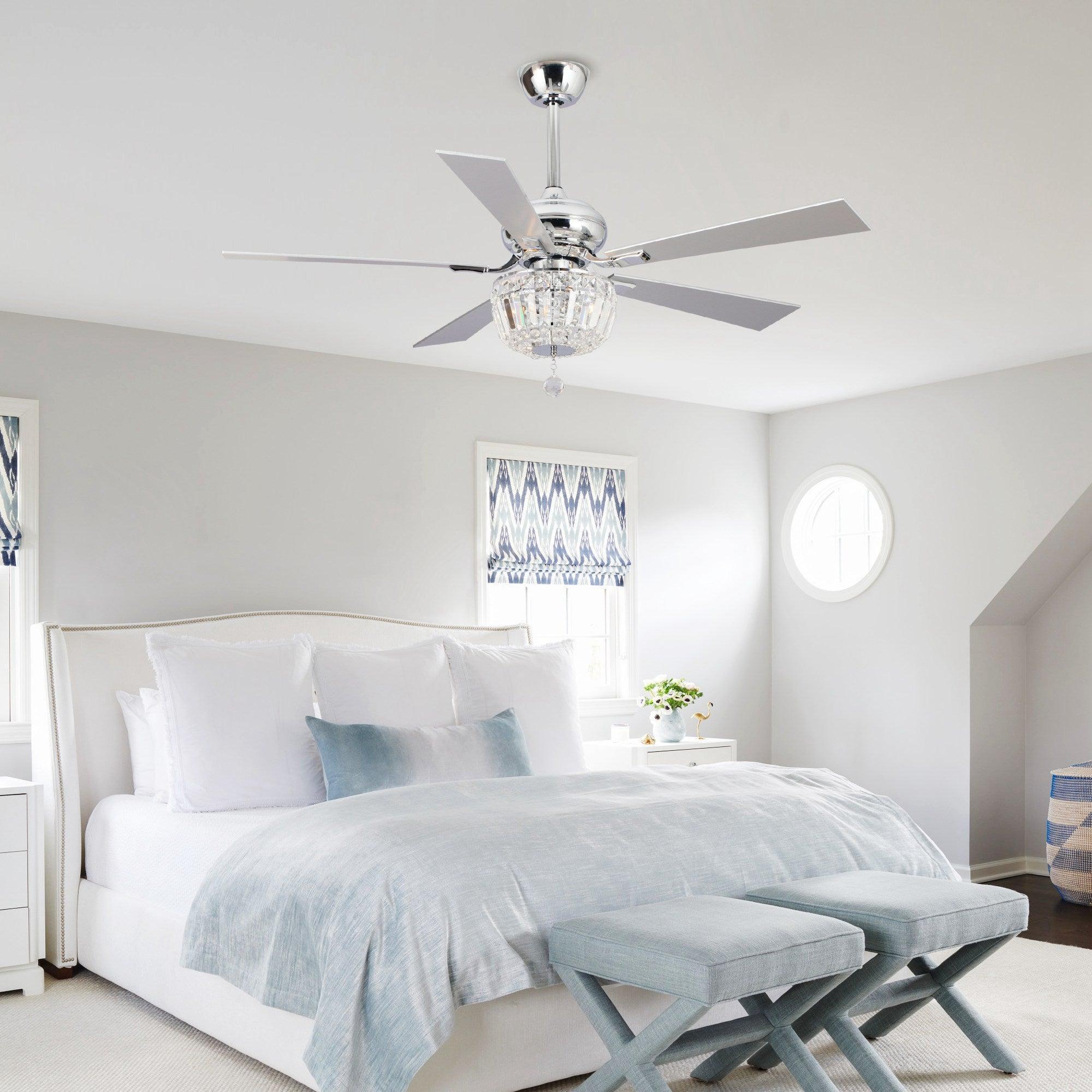 Chrome ceiling fan with crystal light kit and five blades above a bed