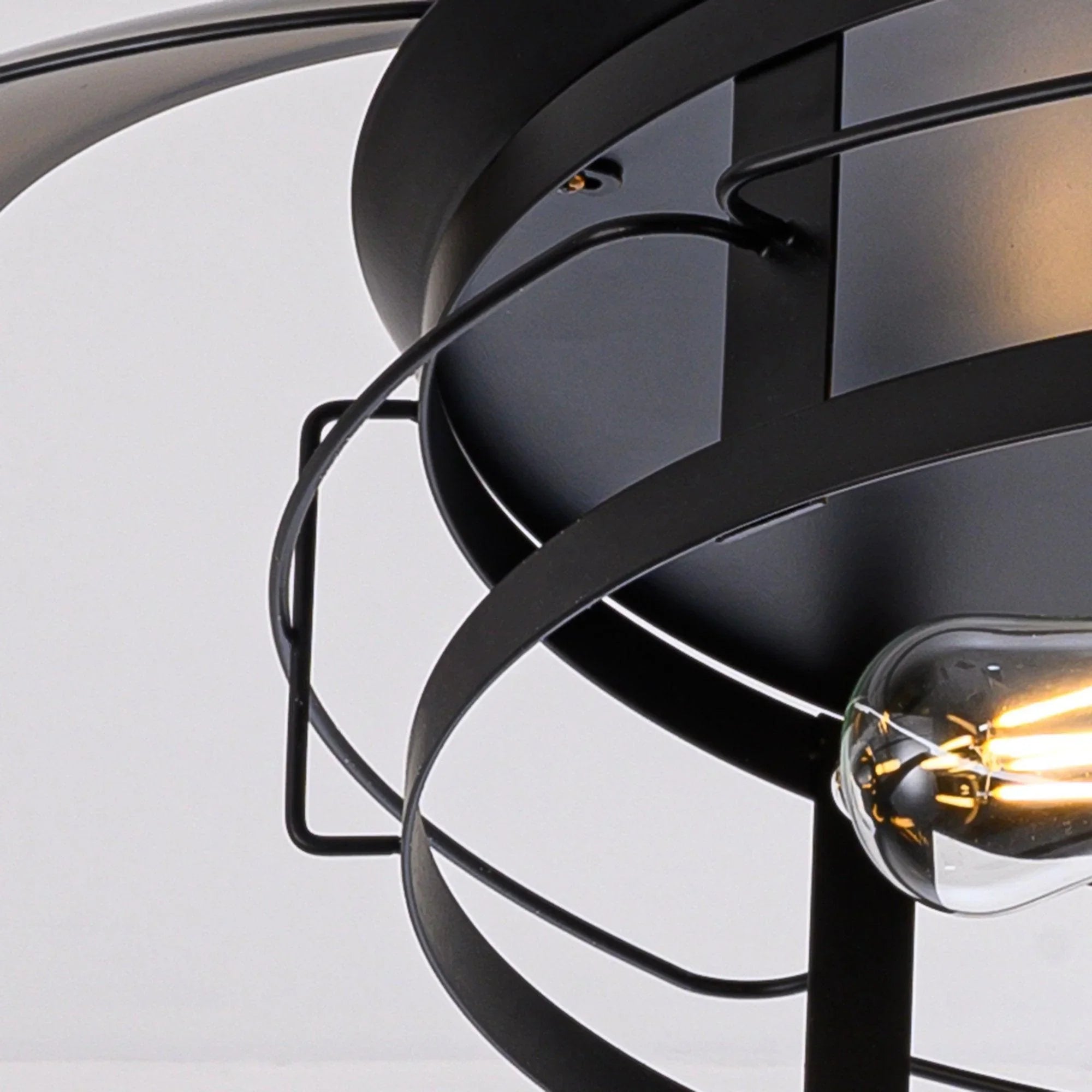 Close-up of black fan light socket with illuminated bulb inside metal cage