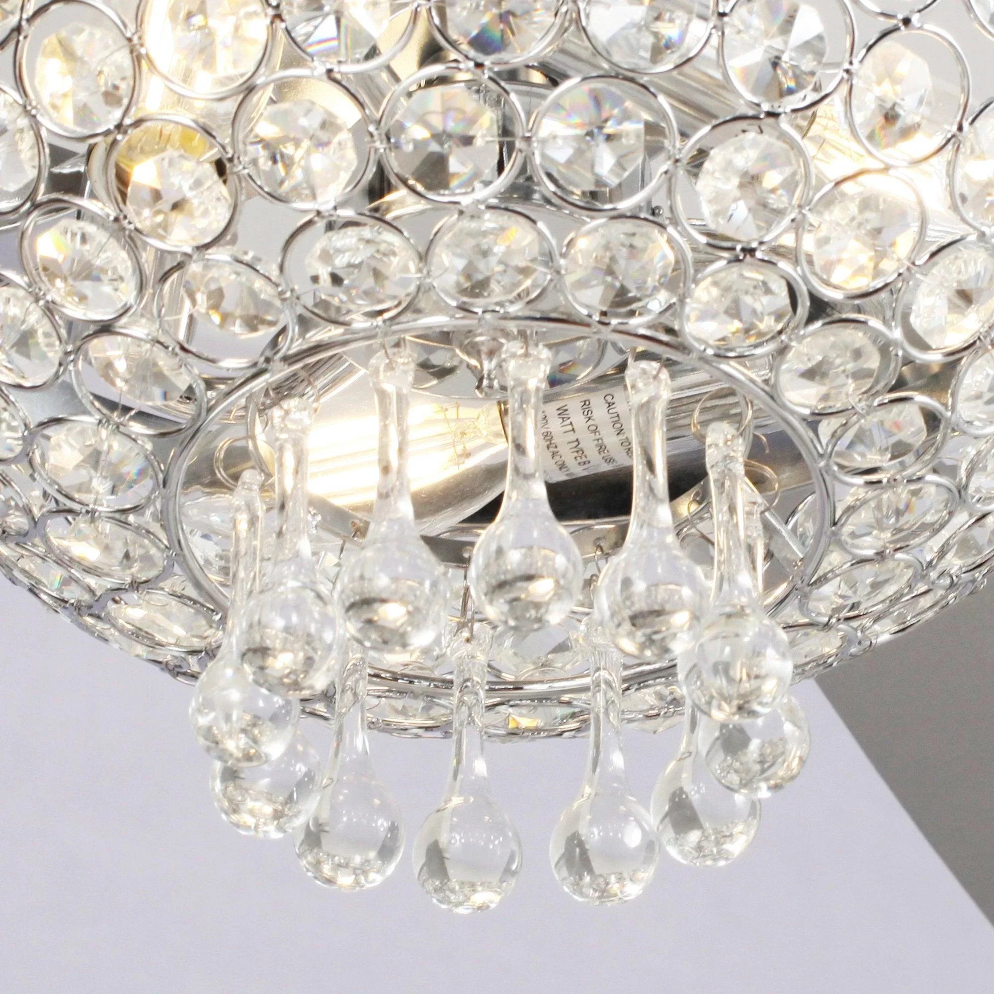 Crystal light shade detail with clear hanging prisms beneath chrome ceiling mount