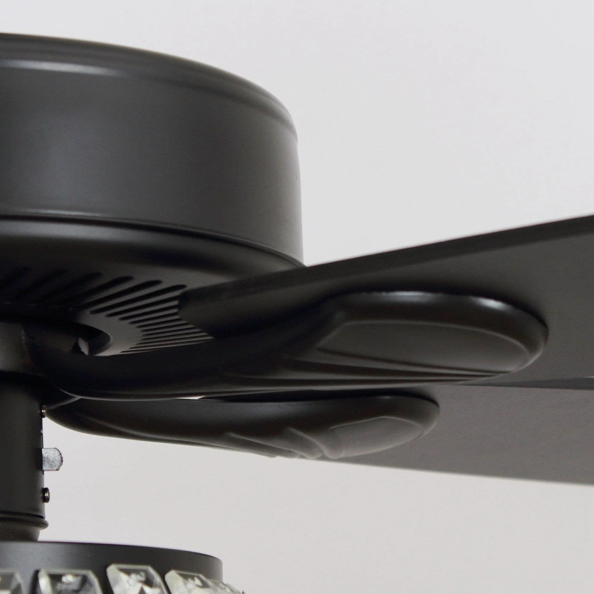 Black fan motor housing with vented grille and curved reversible blade