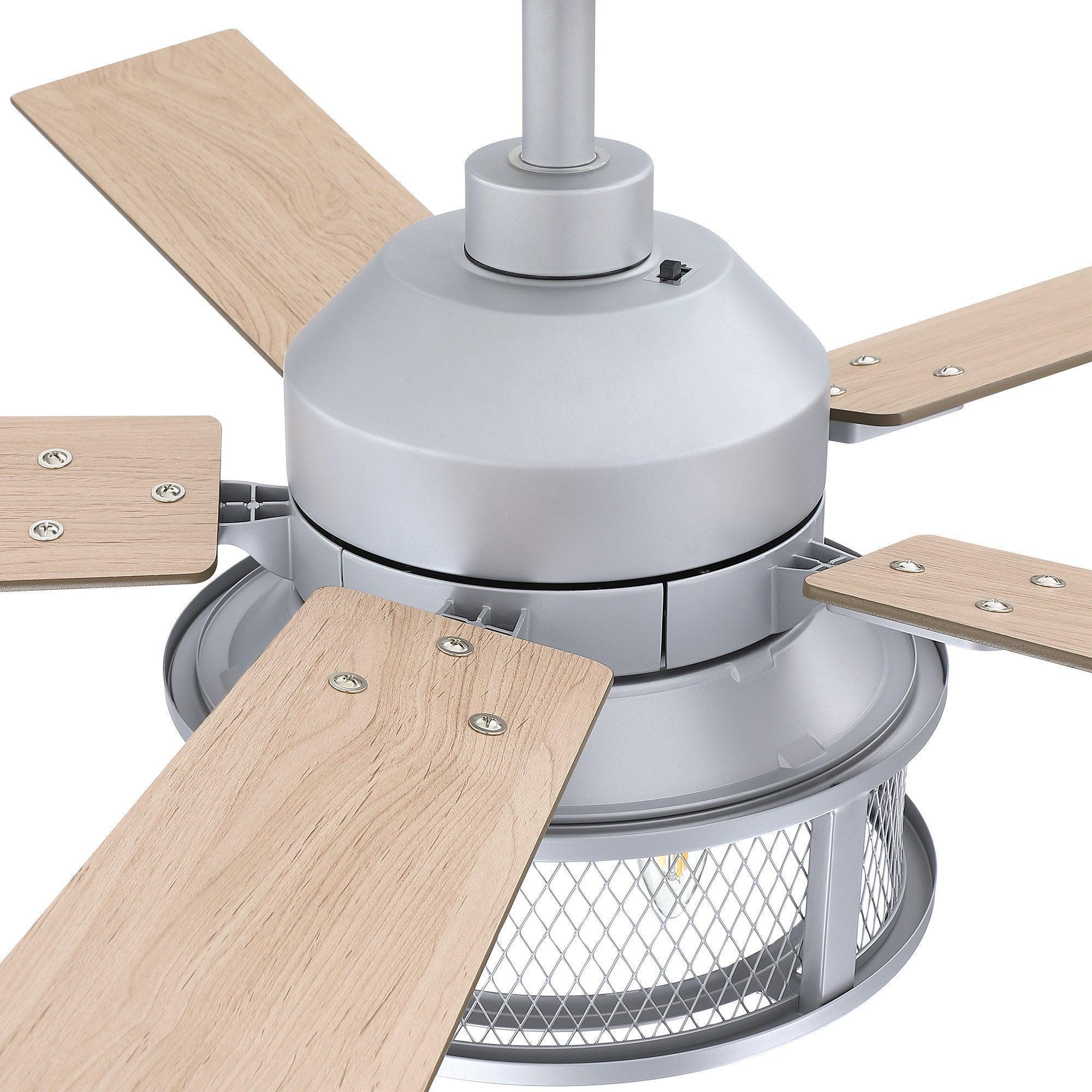 Close-up of silver ceiling fan motor with four wood blades and caged light