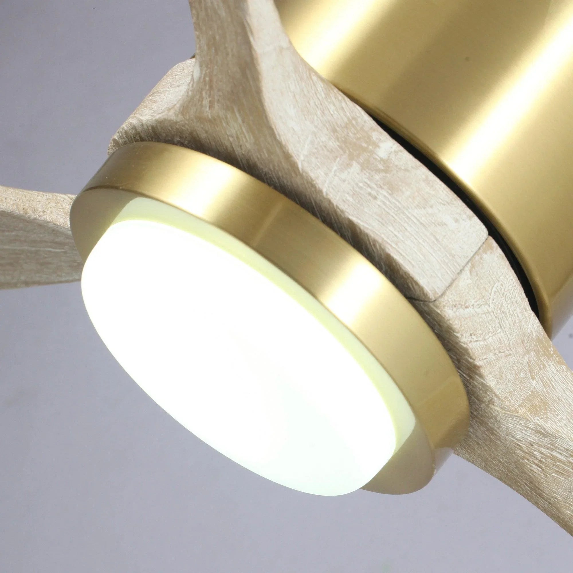 Ceiling fan LED light glowing beneath gold housing with wood-style blade