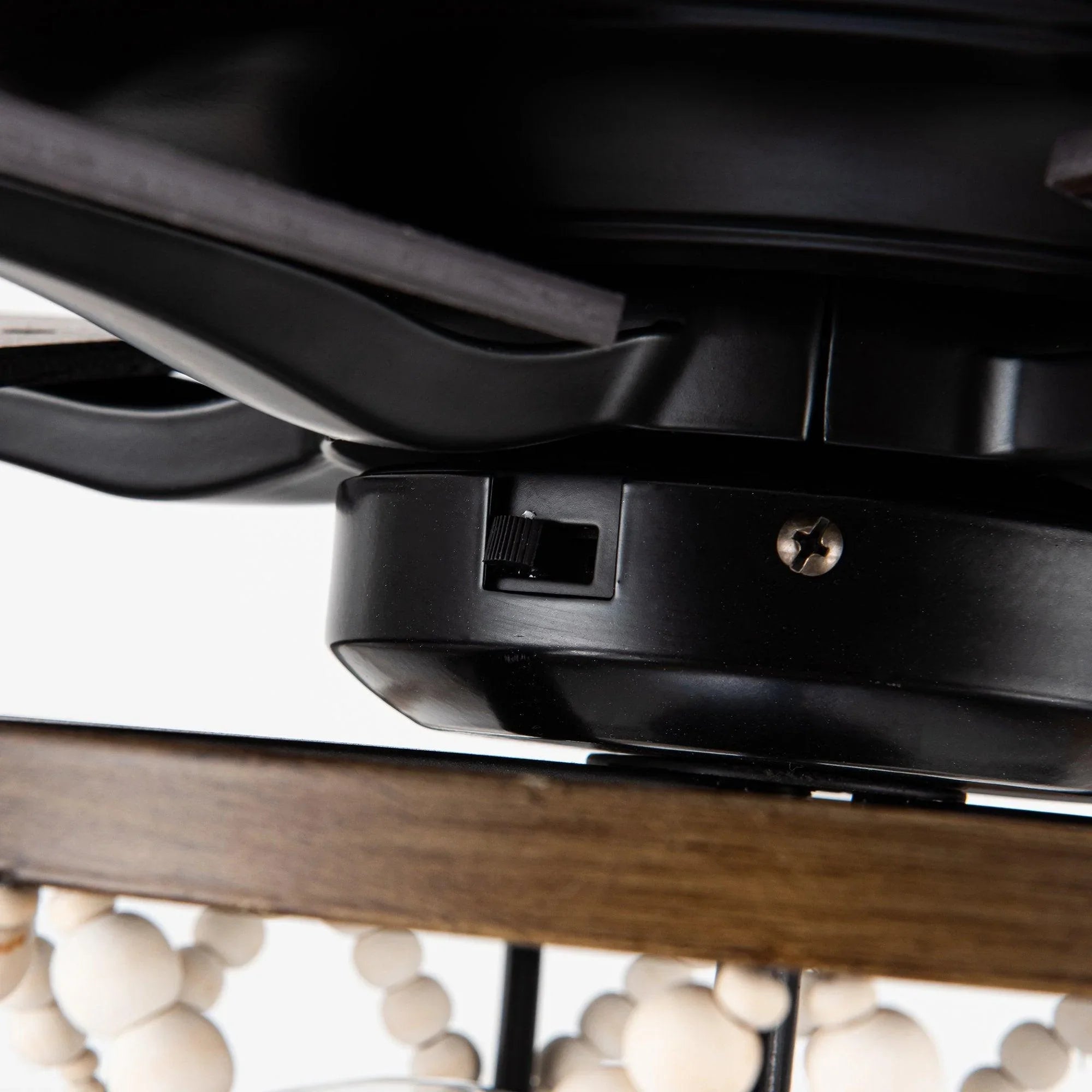 Black ceiling fan motor housing with mounting hardware and dark wood blade edge