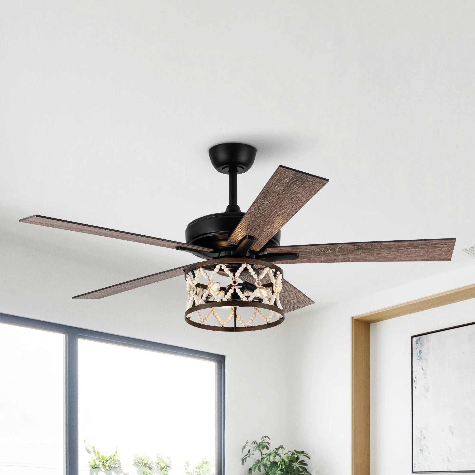 Ceiling fan close-up with black housing, wood-toned blades, and lit decorative cage light