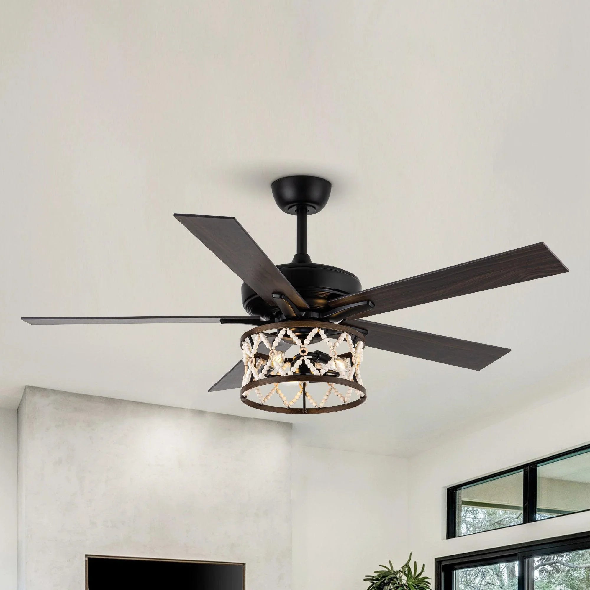 Ceiling fan with black housing, wood-toned reversible blades, and lit decorative cage light