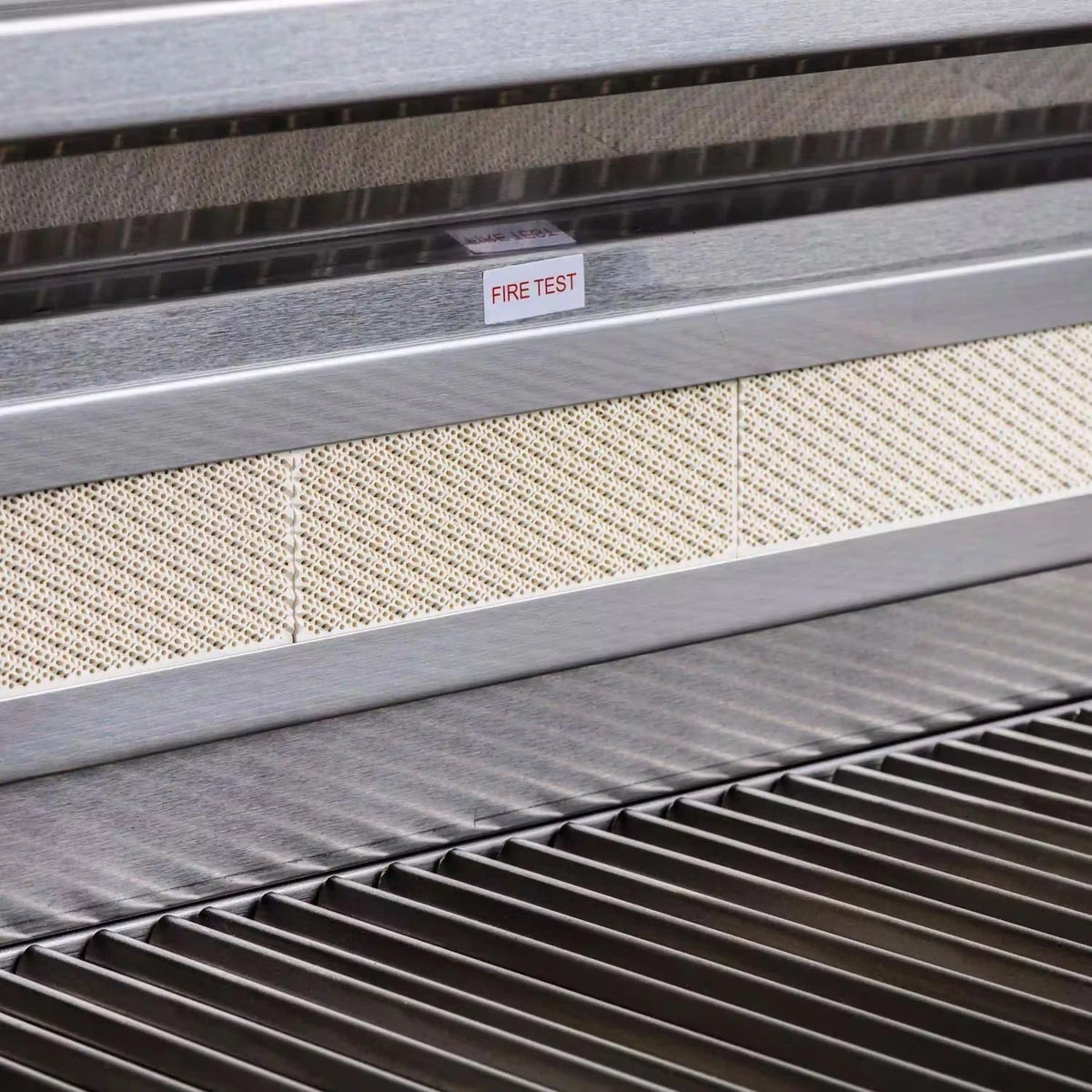Grill safety label reading “FIRE TEST” on metal vent strip