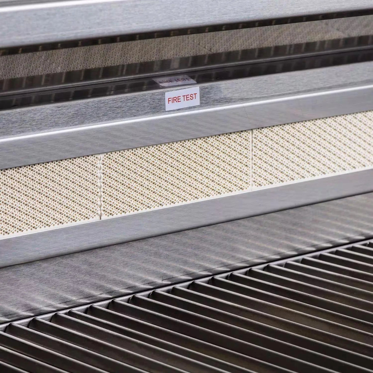 Stainless grill interior with fire test label and perforated grease-collection channel