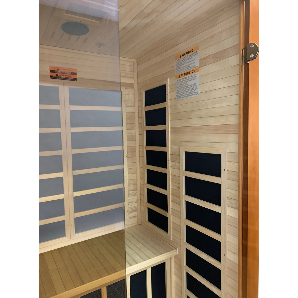 Wood infrared sauna interior with bench platform and paneled walls, door opening view.