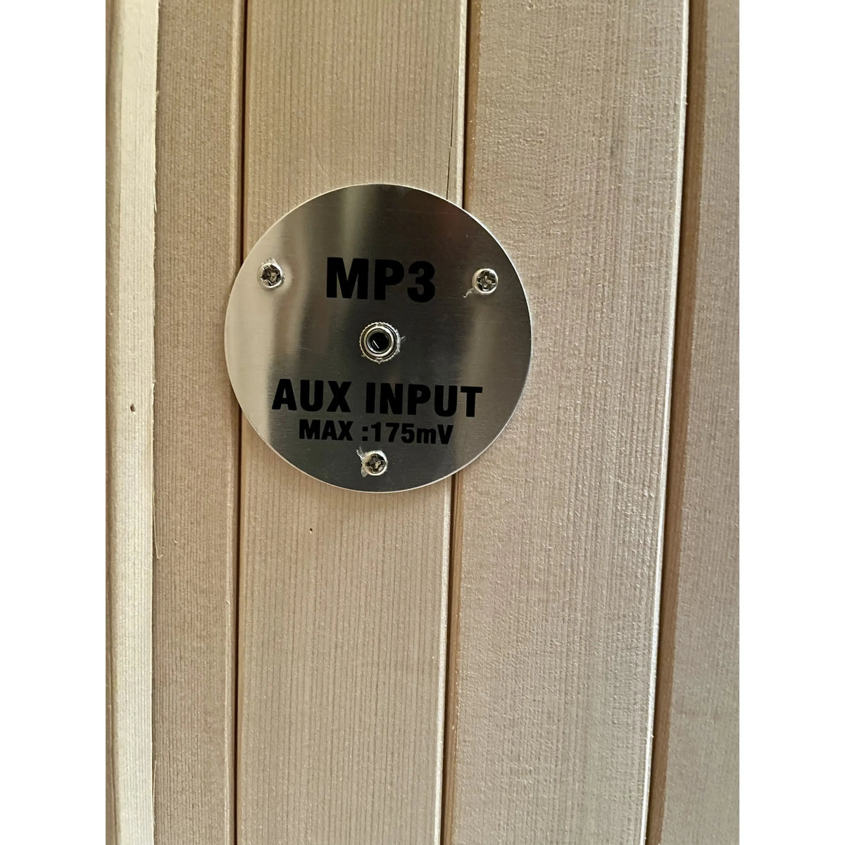 AUX input MP3 port labeled on light wood wall with metal connector face.