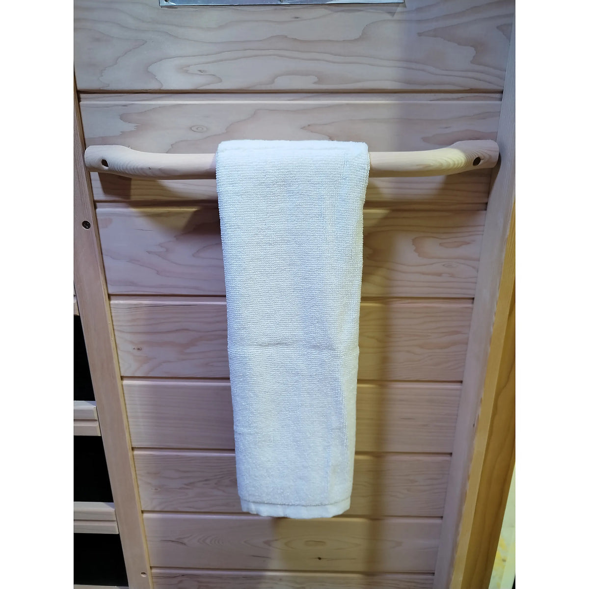 Wooden infrared sauna towel bar with white towel centered on the bar