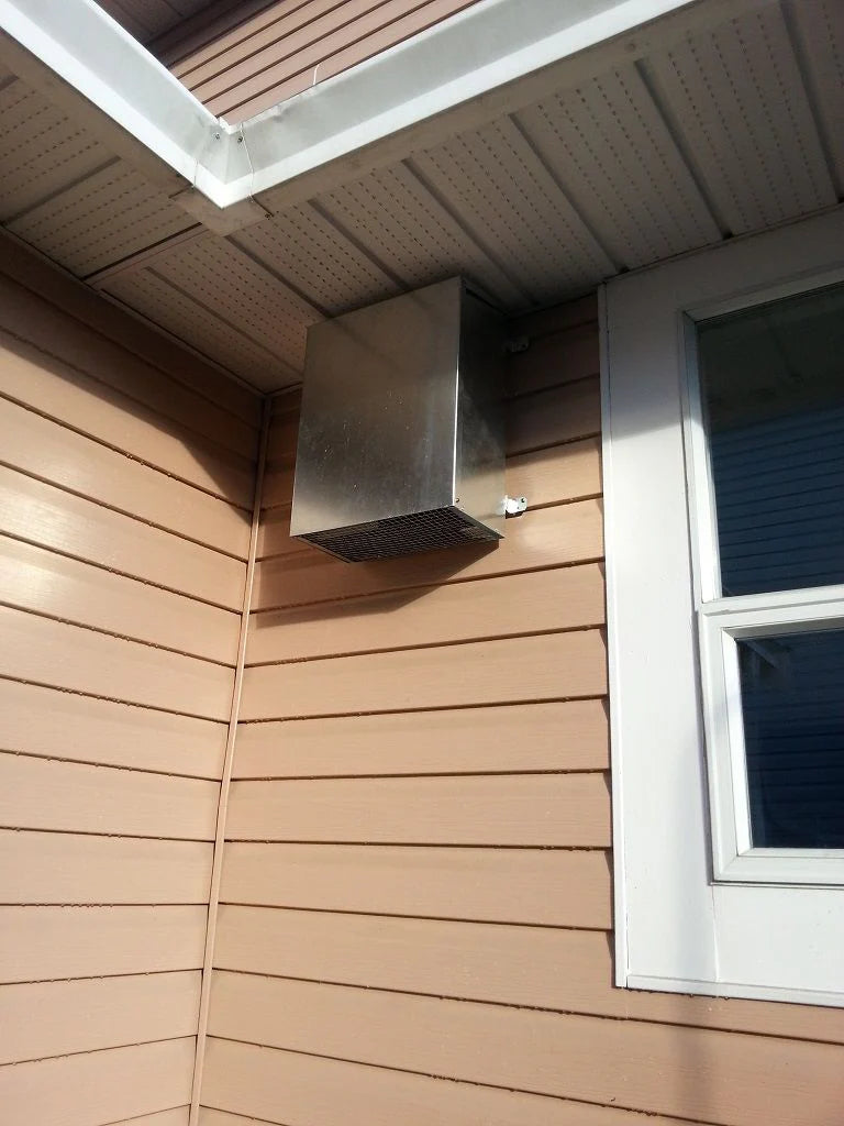 Outdoor wall blower vent hood mounted on exterior siding under a soffit