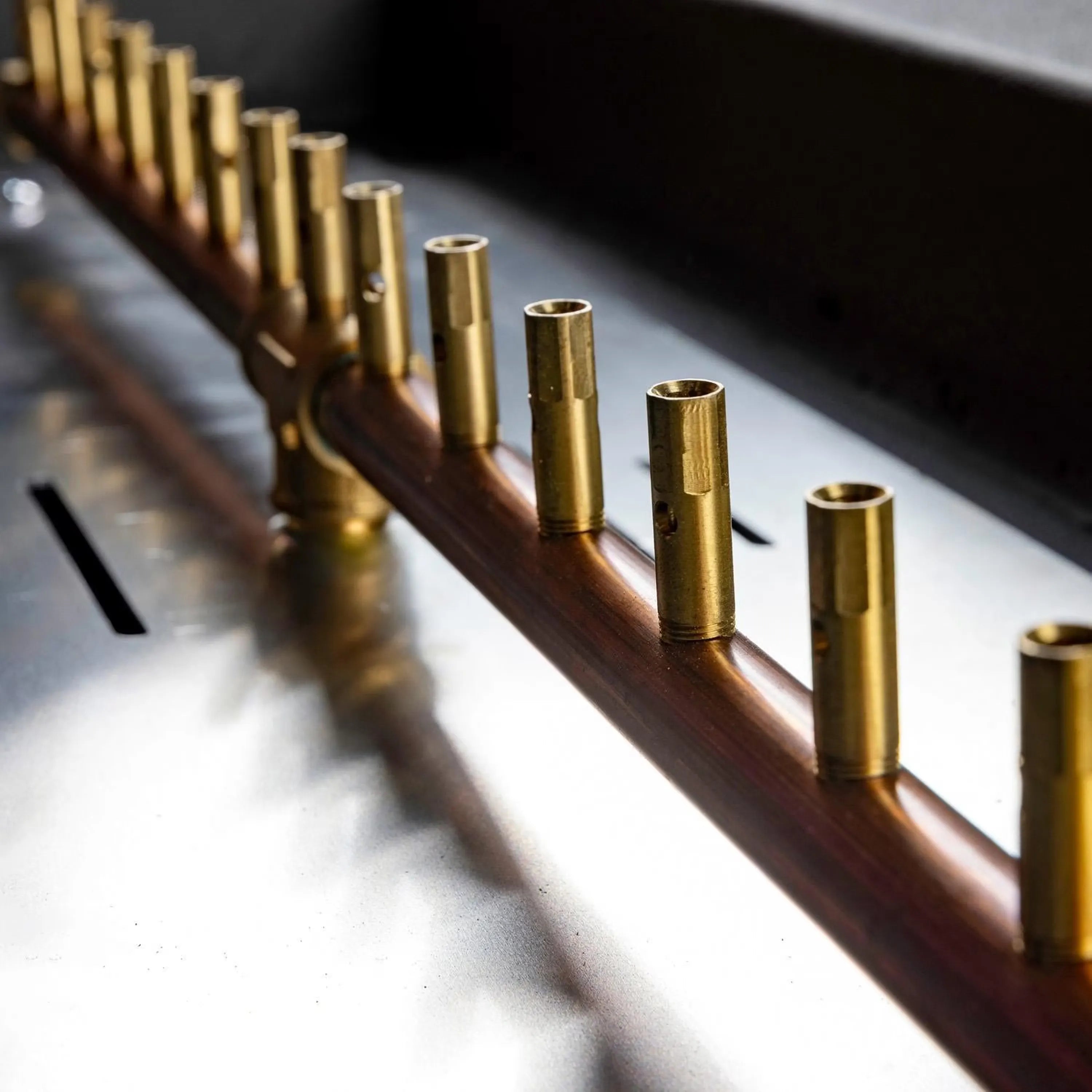 Brass gas burner tubes inside rectangular fire pit, close-up view