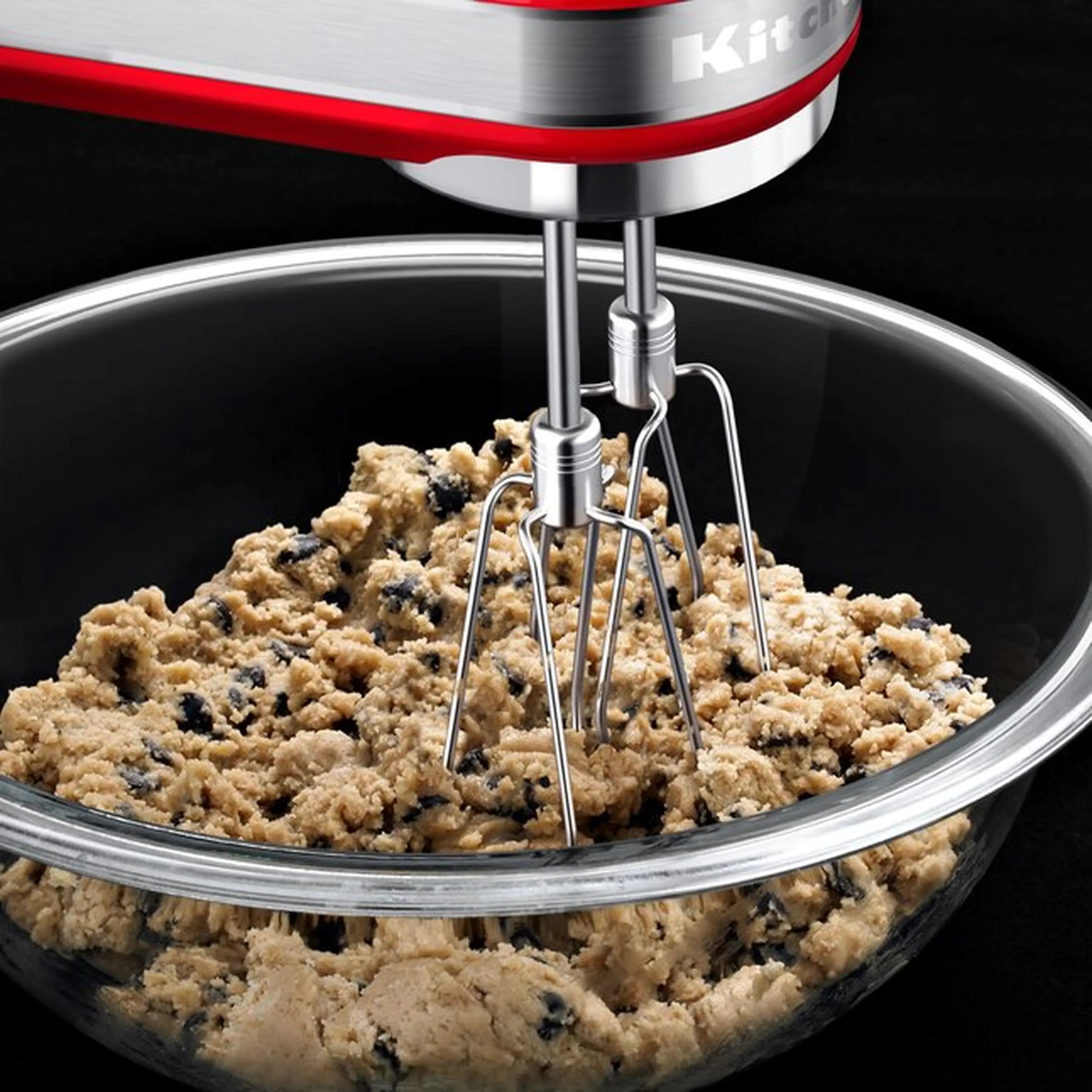 KitchenAid hand mixer whipping beige batter in a stainless mixing bowl