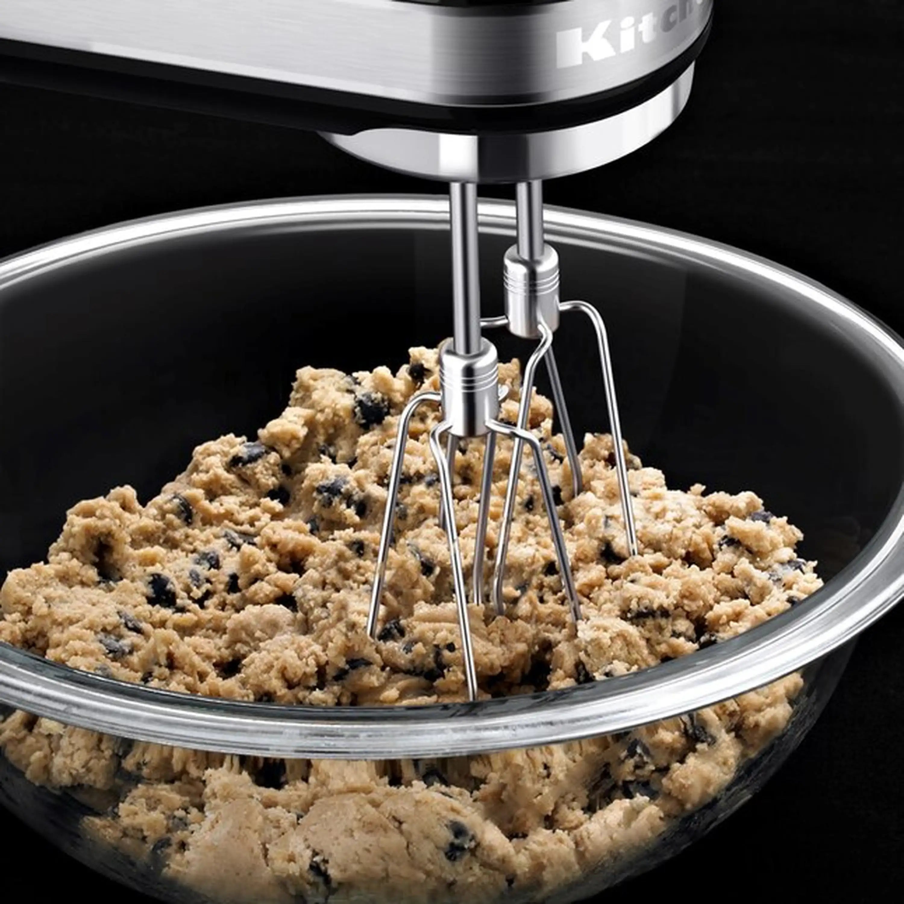 KitchenAid hand mixer beaters mixing dough in a stainless bowl