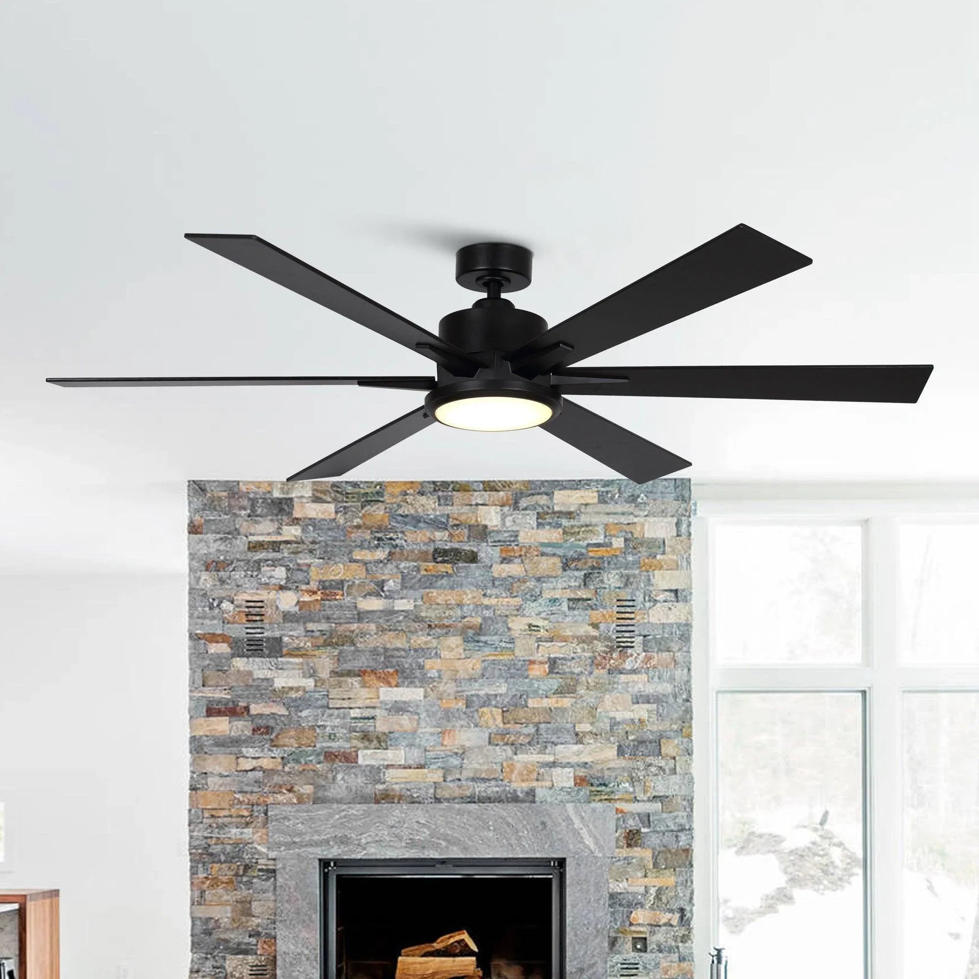 Black ceiling fan with five blades above stone fireplace with integrated light
