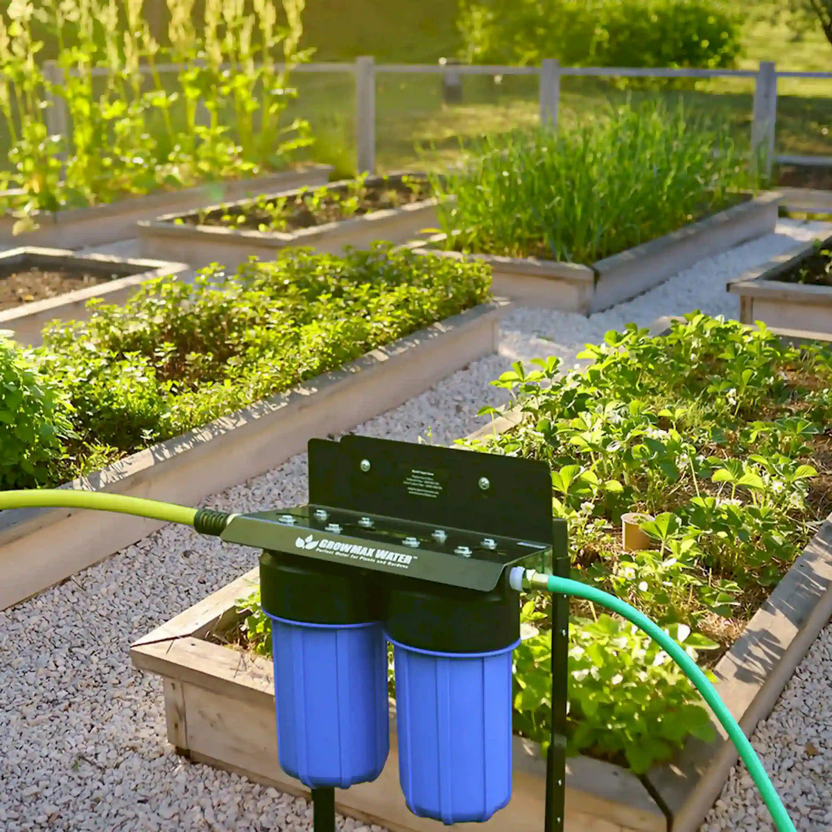 Outdoor garden water filtration system on raised bed with green garden hose