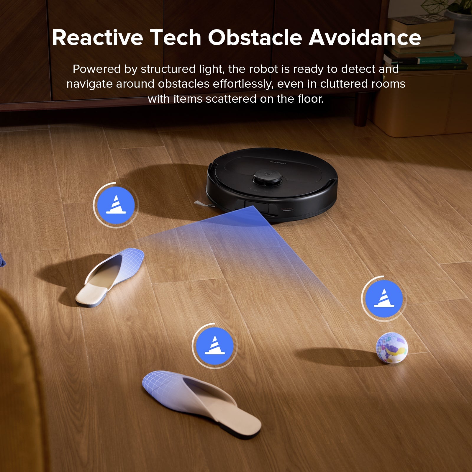 Black robot vacuum on wood floor avoiding obstacles like slippers and small items
