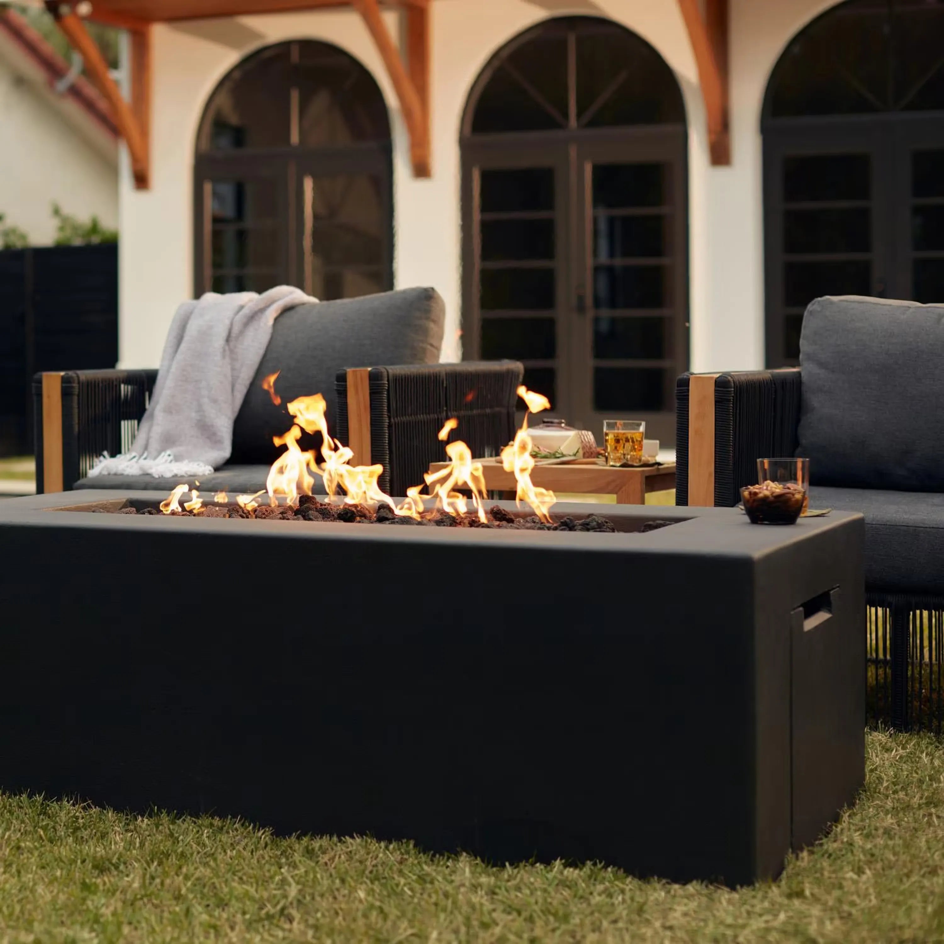 Rectangular gas fire pit table with dark concrete finish, open burner with flames