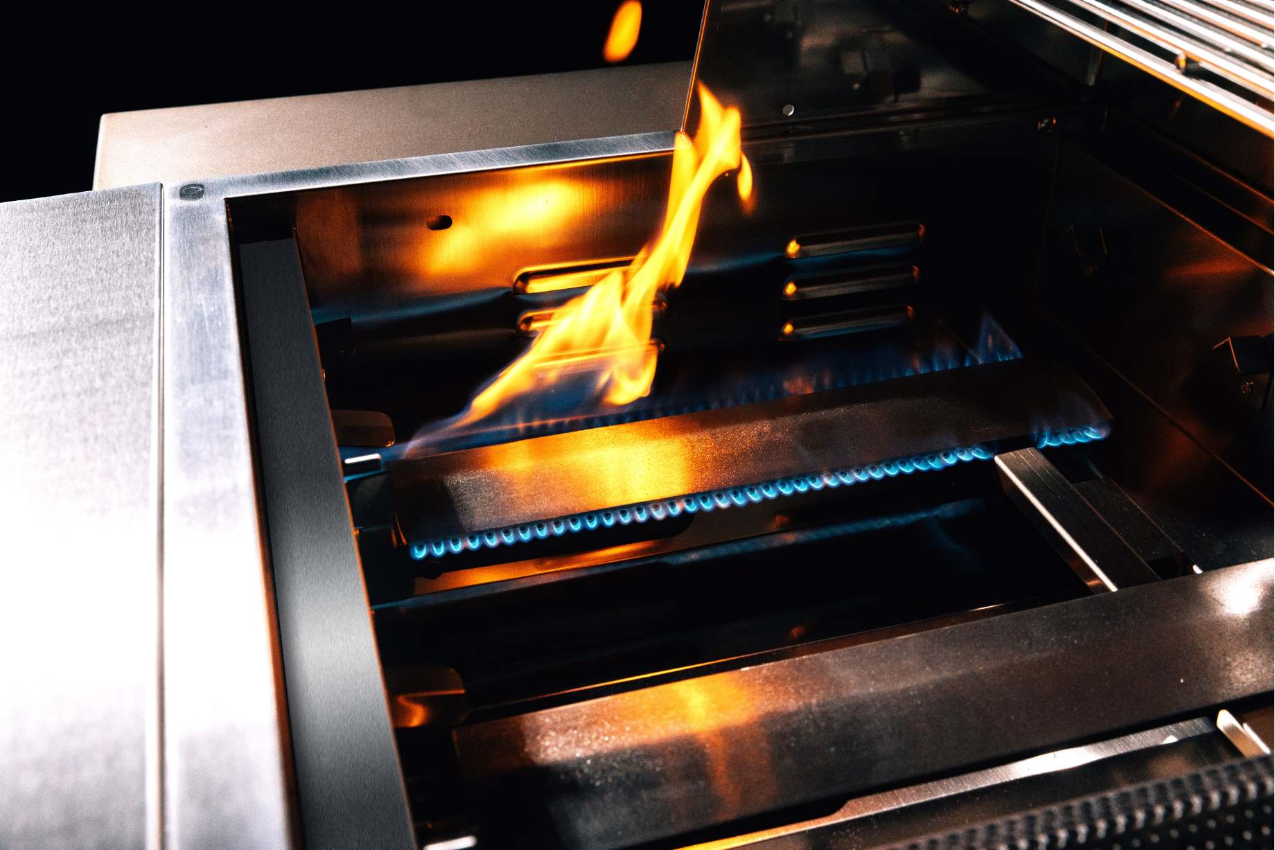 Stainless built-in propane gas grill with visible burners and active flames