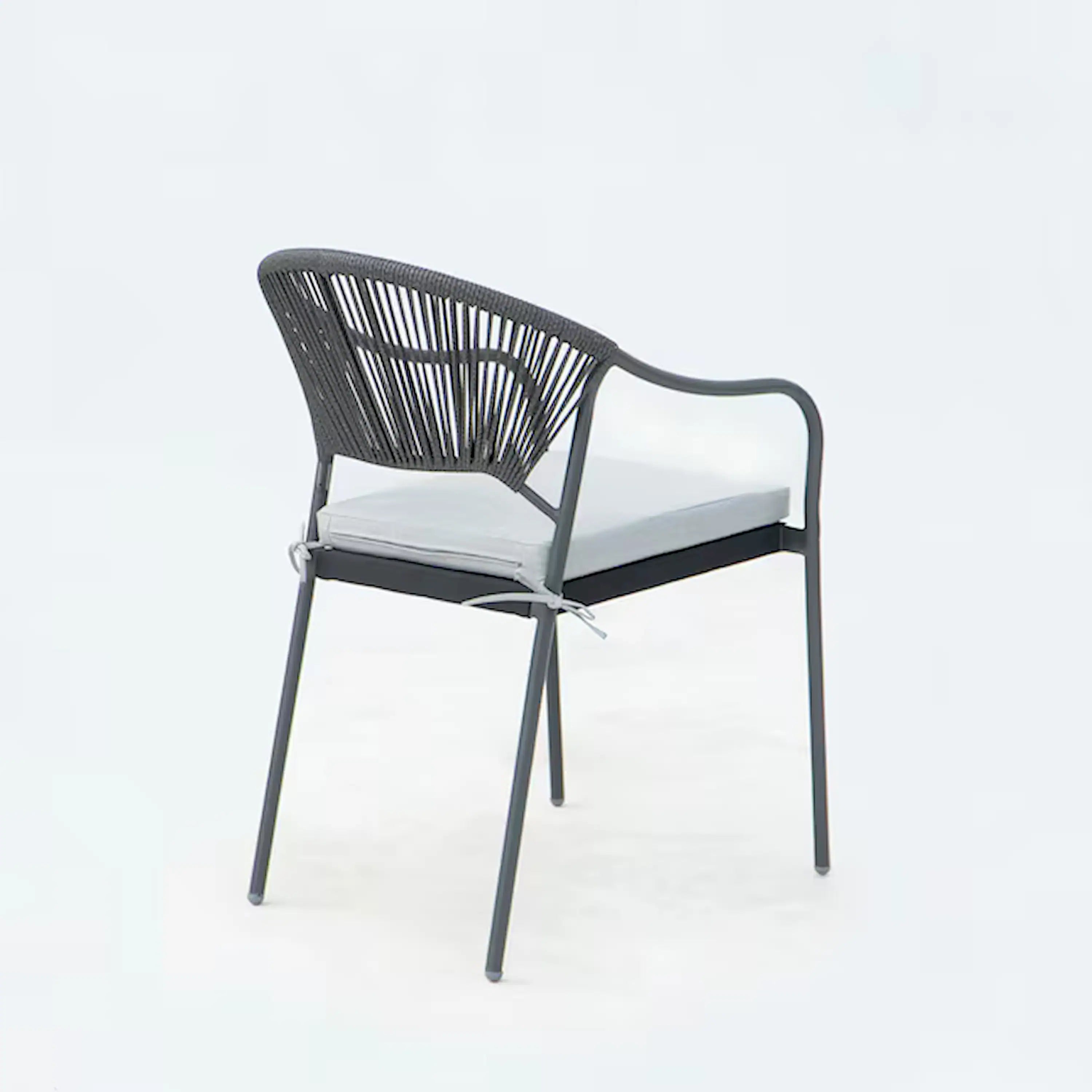 Outdoor patio dining chair with black rope back and white seat cushion, side angle view.