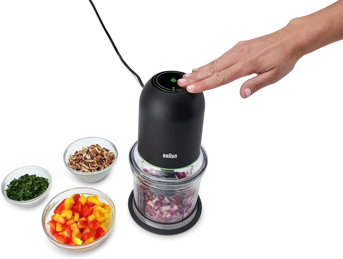 Black mini food chopper with clear jar and hand pressing the top button
