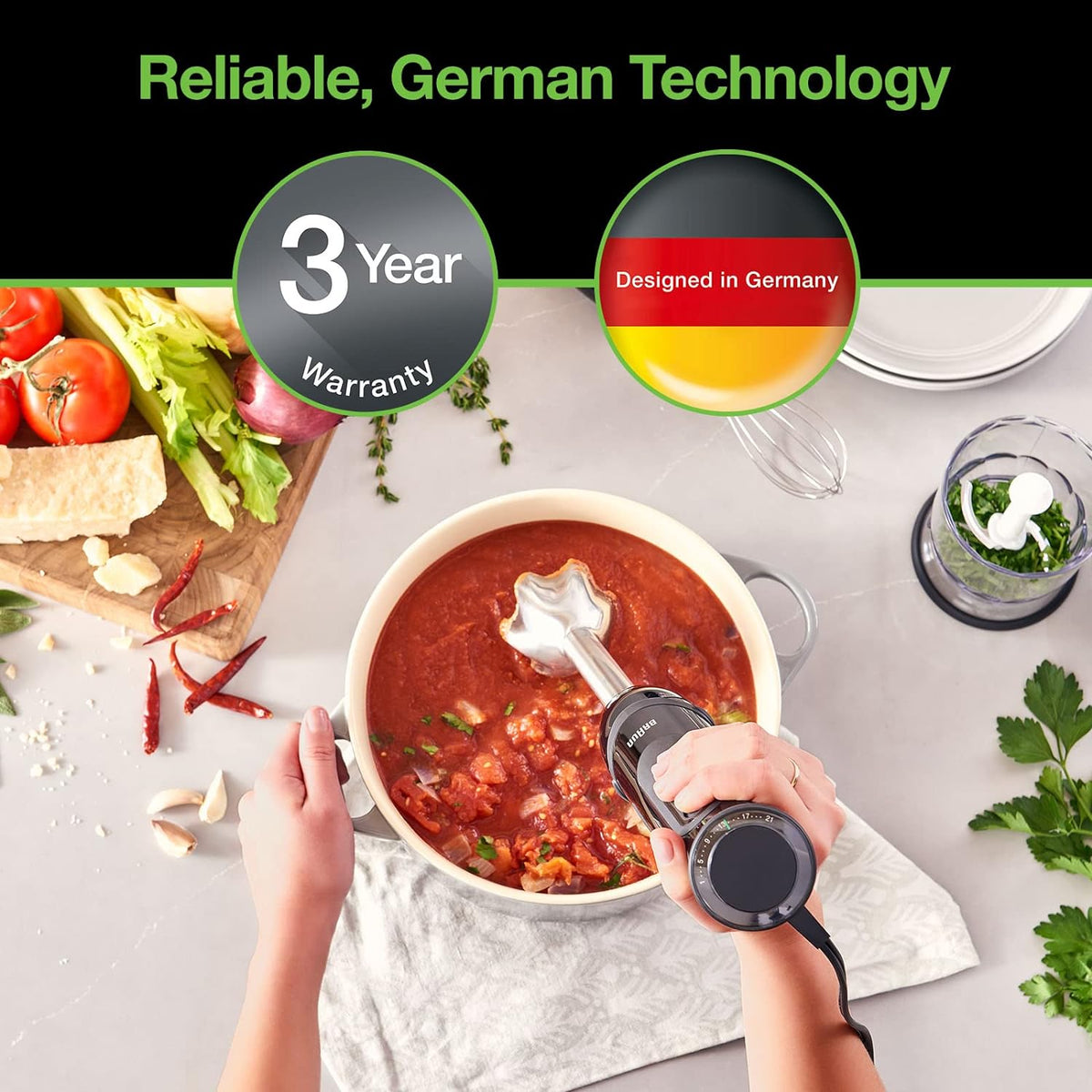 Black immersion blender mixing soup in a white cooking pot